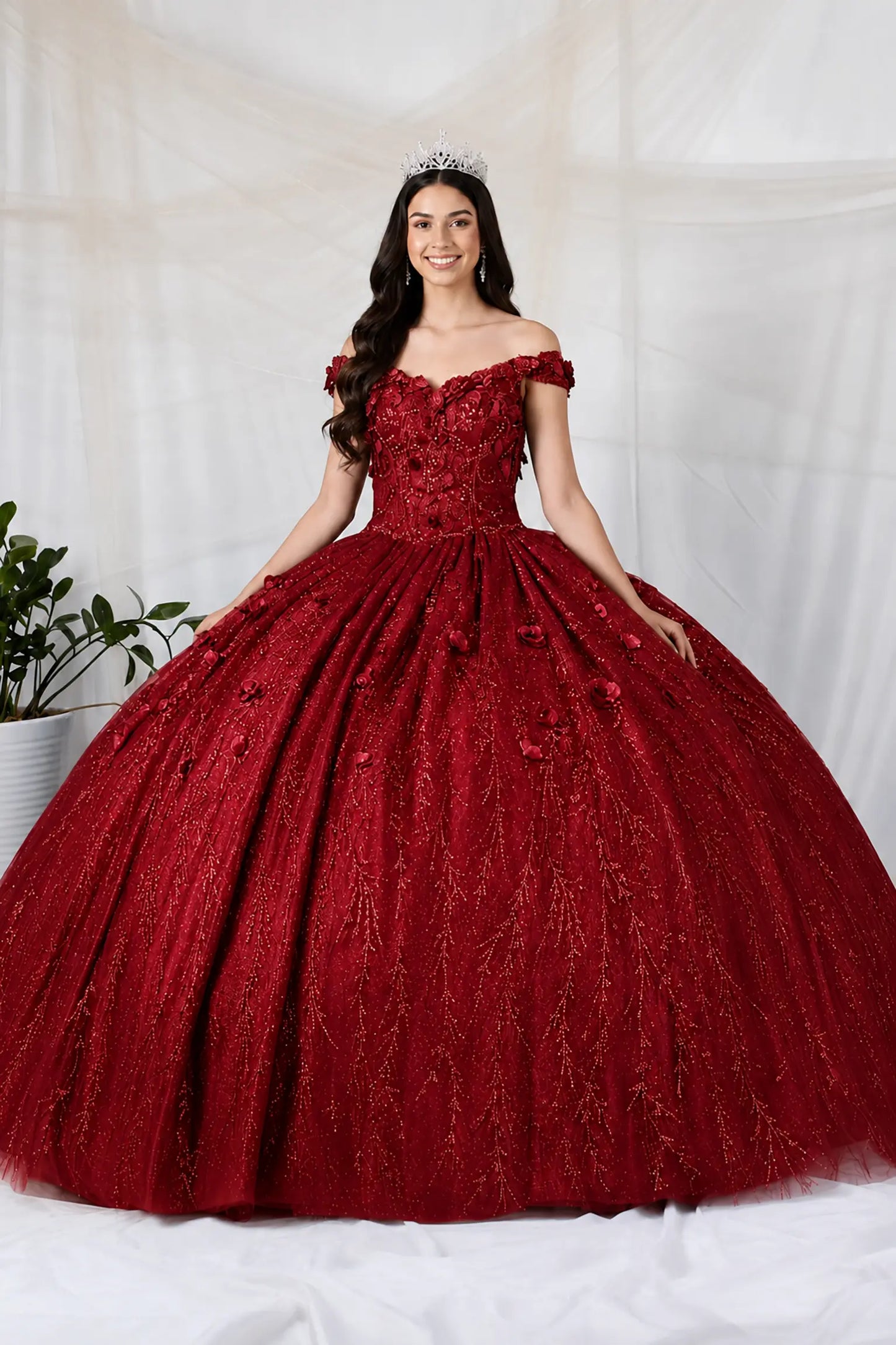Front view of a burgundy quinceanera dress with 3D floral appliques, glittered fabric, and detachable sheer flowing cape