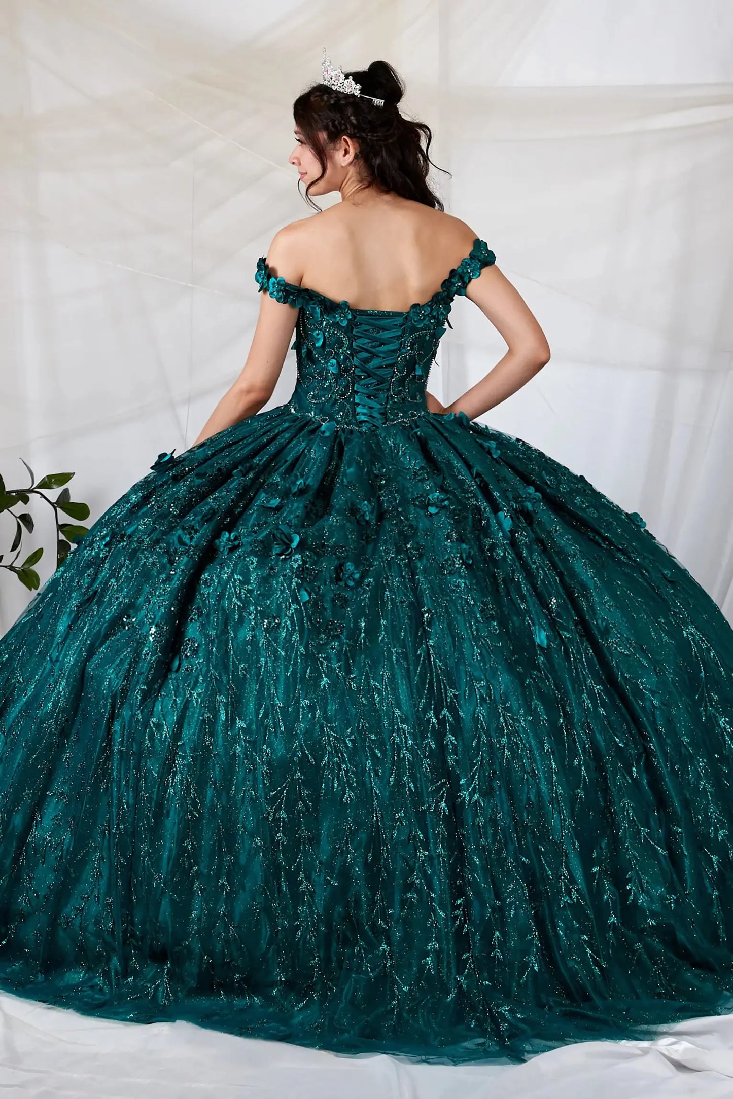 Back view of a green quinceanera dress with lace-up corset, 3D floral appliques and glitter tulle skirt