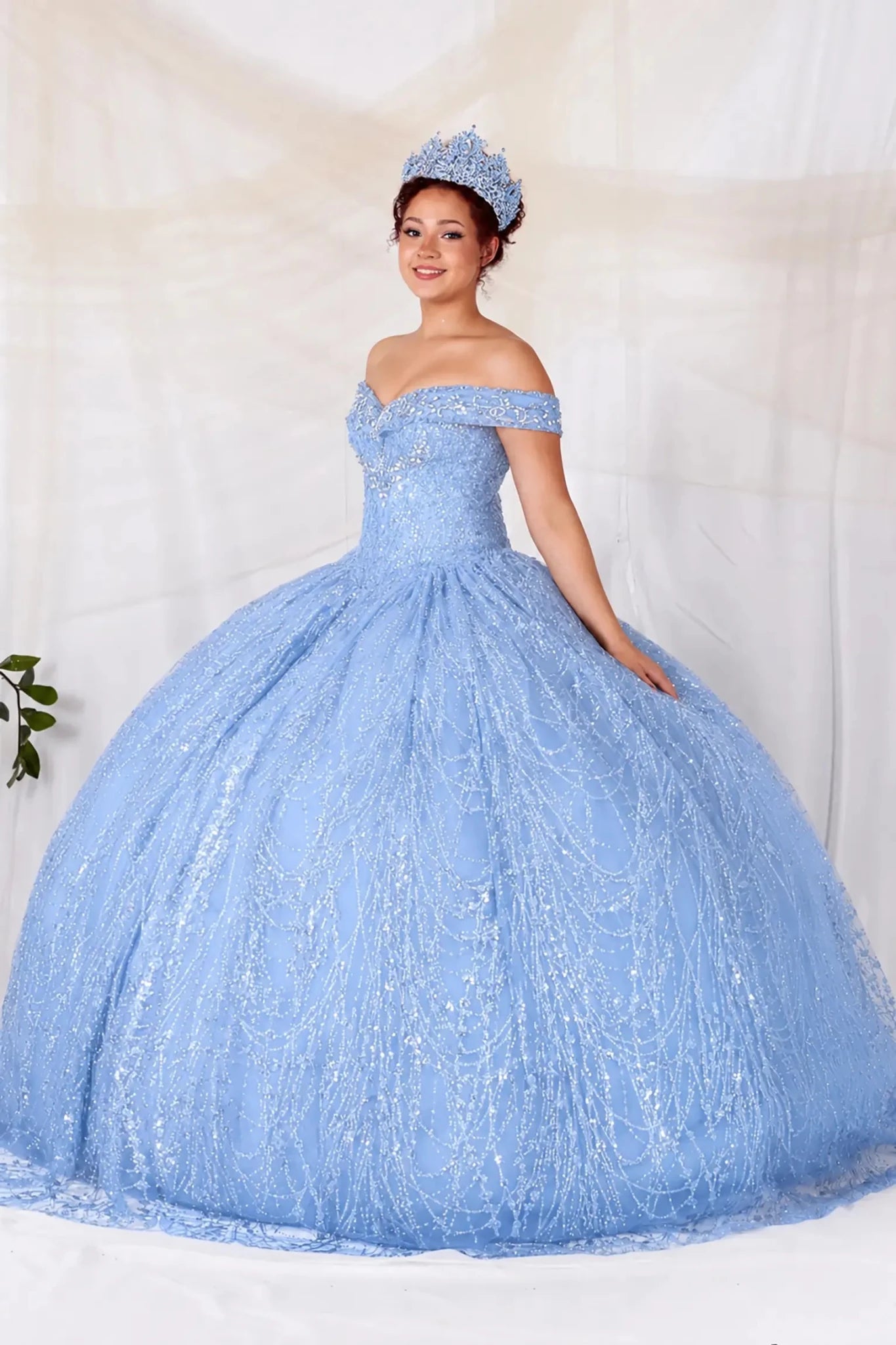 Woman in a blue sparkly quinceanera ball gown with off the shoulder design