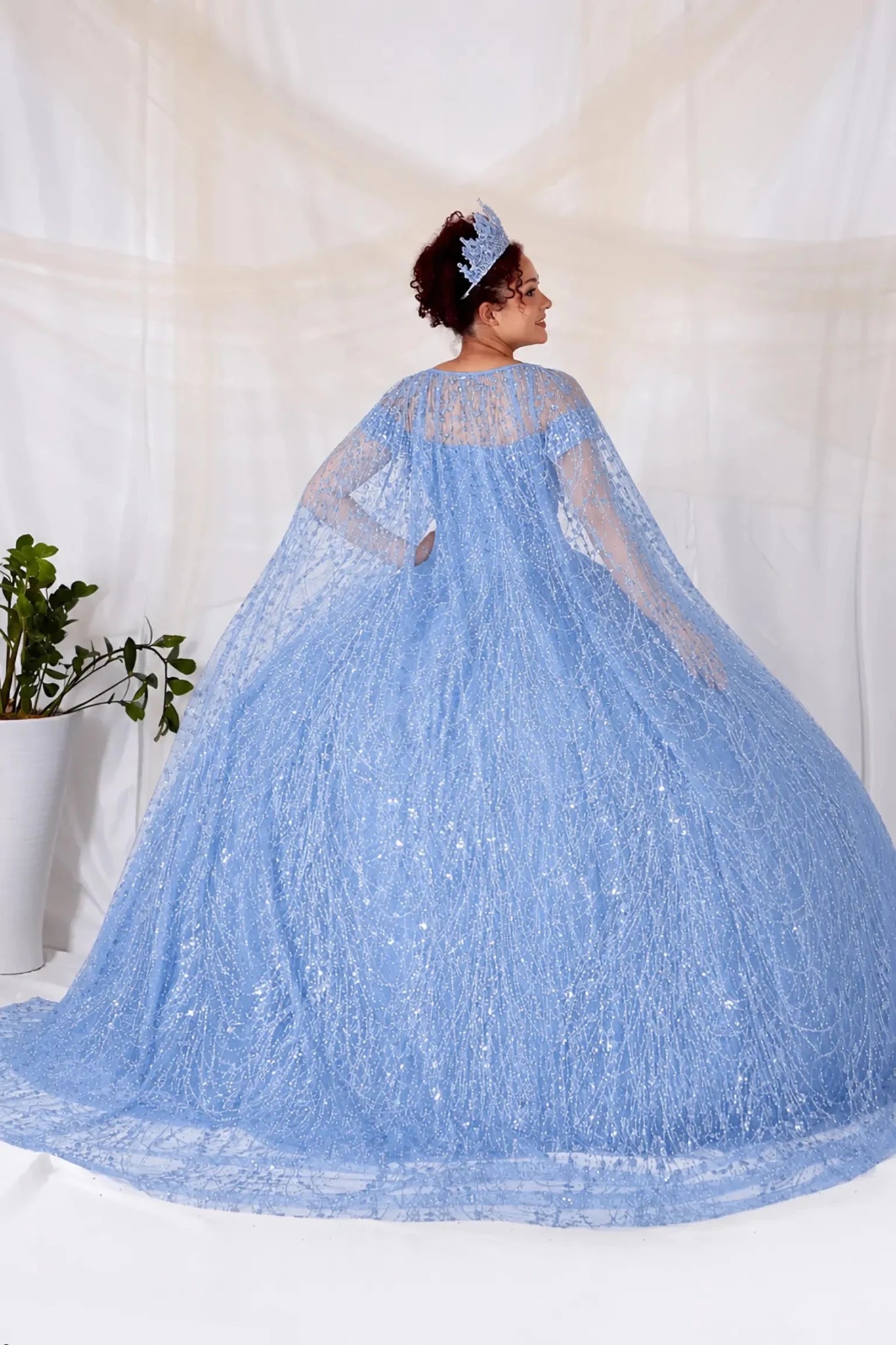 Person wearing a blue sequin lace quinceanera dress with a cape 