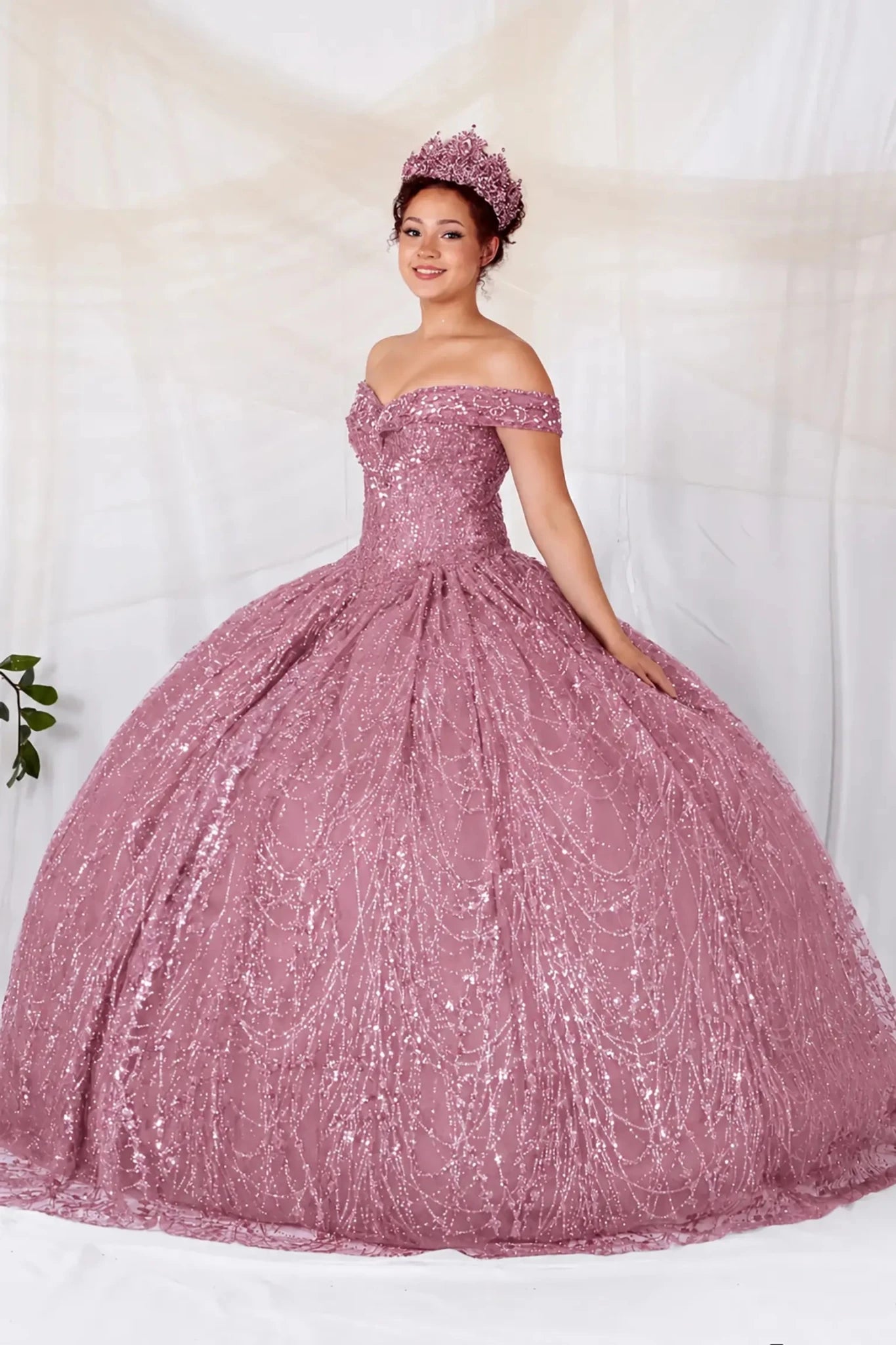 Woman in a sparkly rose gold quinceanera dress with off the shoulder design