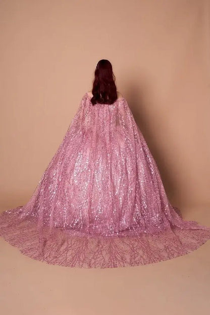 Back-Facing of a woman wearing Dusty rose formal dress featuring open back sweep train and soft cape detail