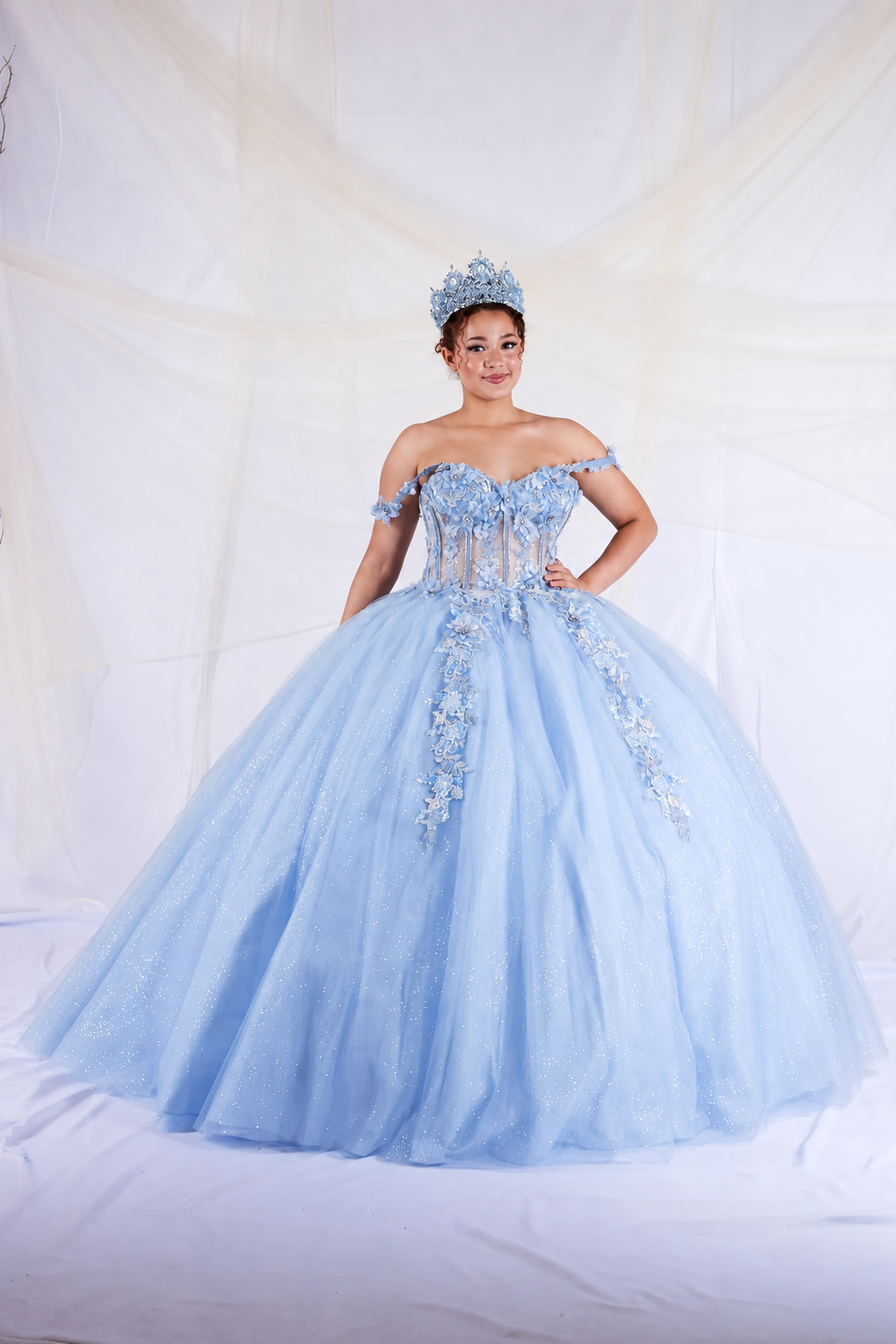 Light Blue quinceañera dress showcases detachable sheer cape sleeves above floral appliqué corset bodice.