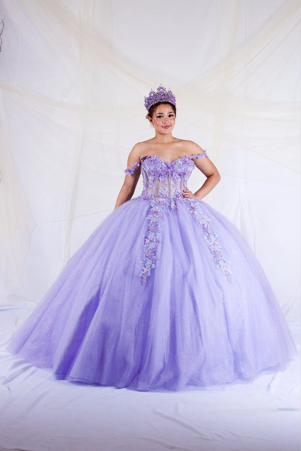 Lilac quinceañera dress showcases detachable sheer cape sleeves above floral appliqué corset bodice.