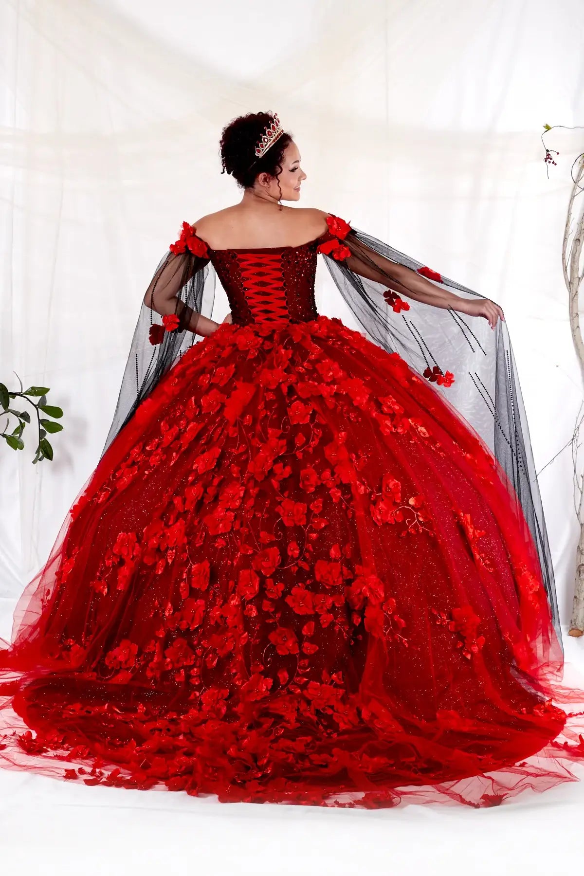 Back-Facing of a woman wearing Two-tone formal gown featuring layered skirt open back and detachable cape detail