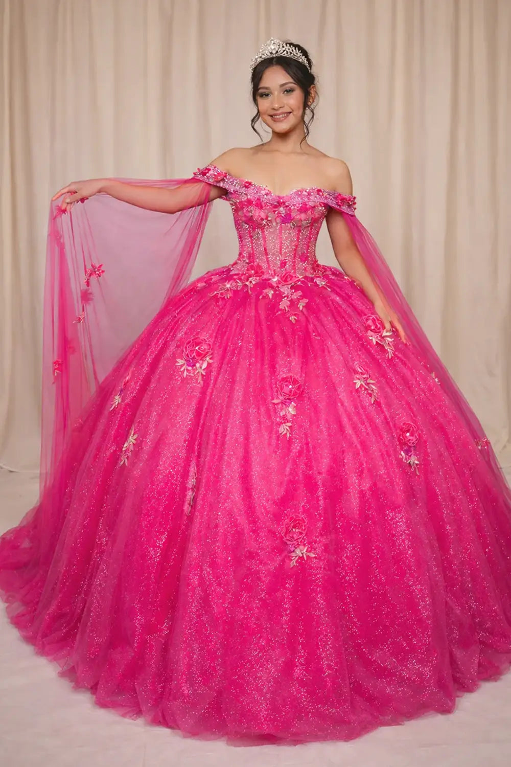 Front-Facing of a woman wearing Hot pink quinceanera gown with sheer lace bodice off-shoulder neckline and flowing skirt with removable shoulder cape