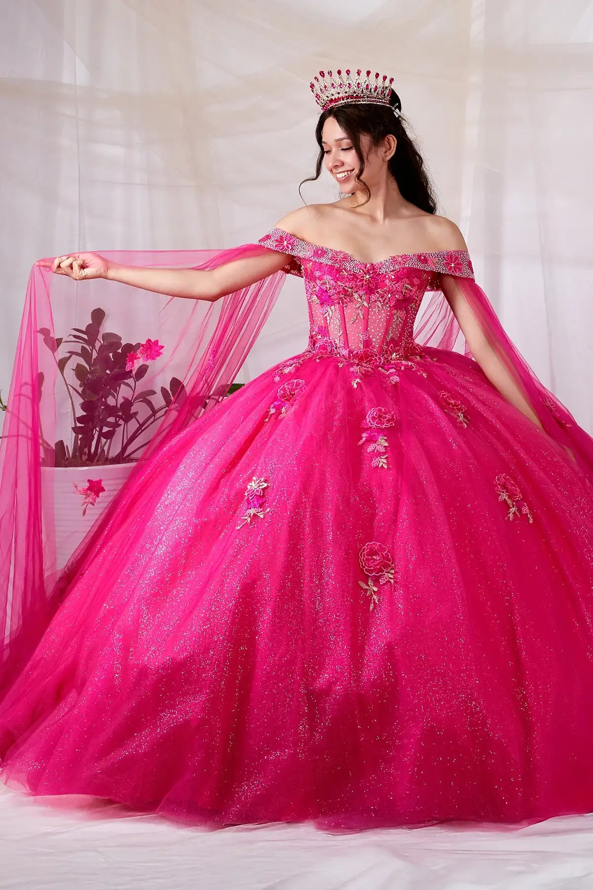 Front View of a woman wearing Hot pink dress showcasing layered skirt movement and removable cape drape from shoulders