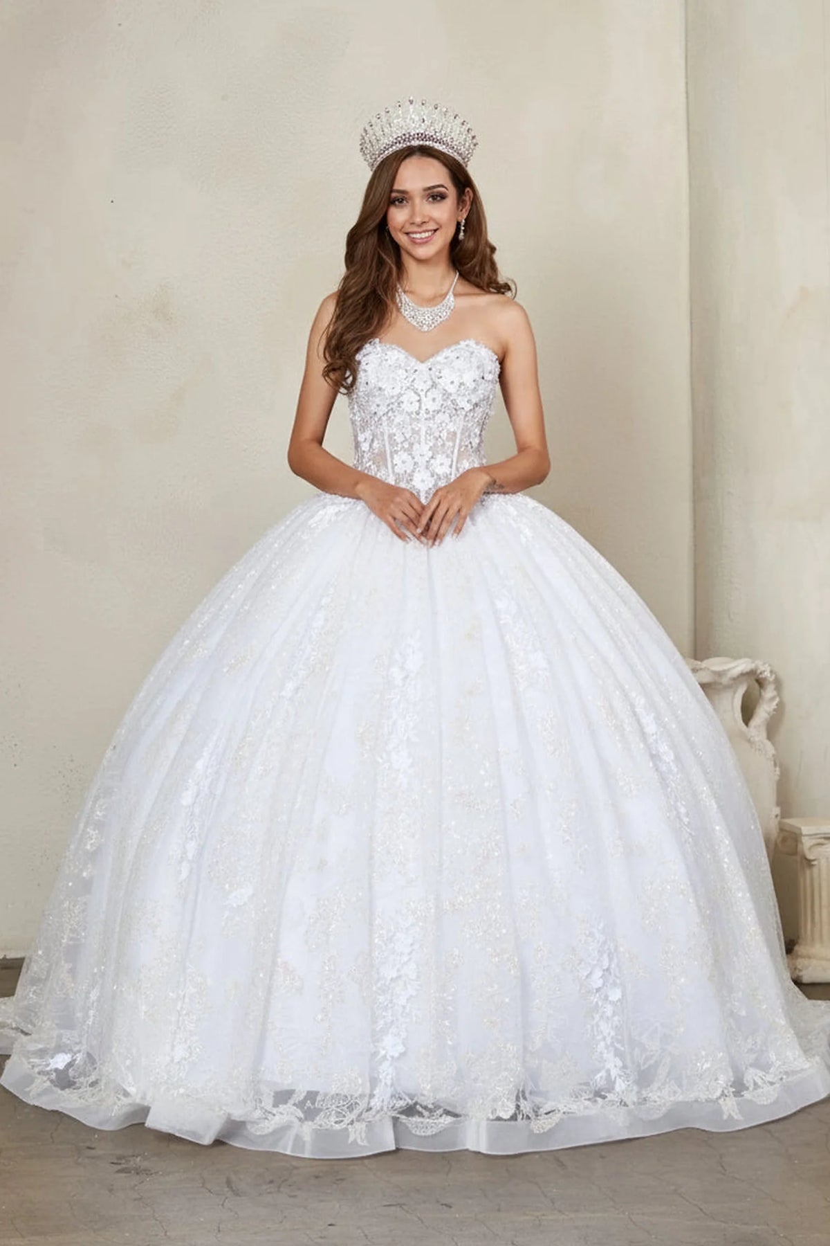White quinceañera dress showcases butterfly sequins and 3d floral details above glittering tulle ball gown skirt.