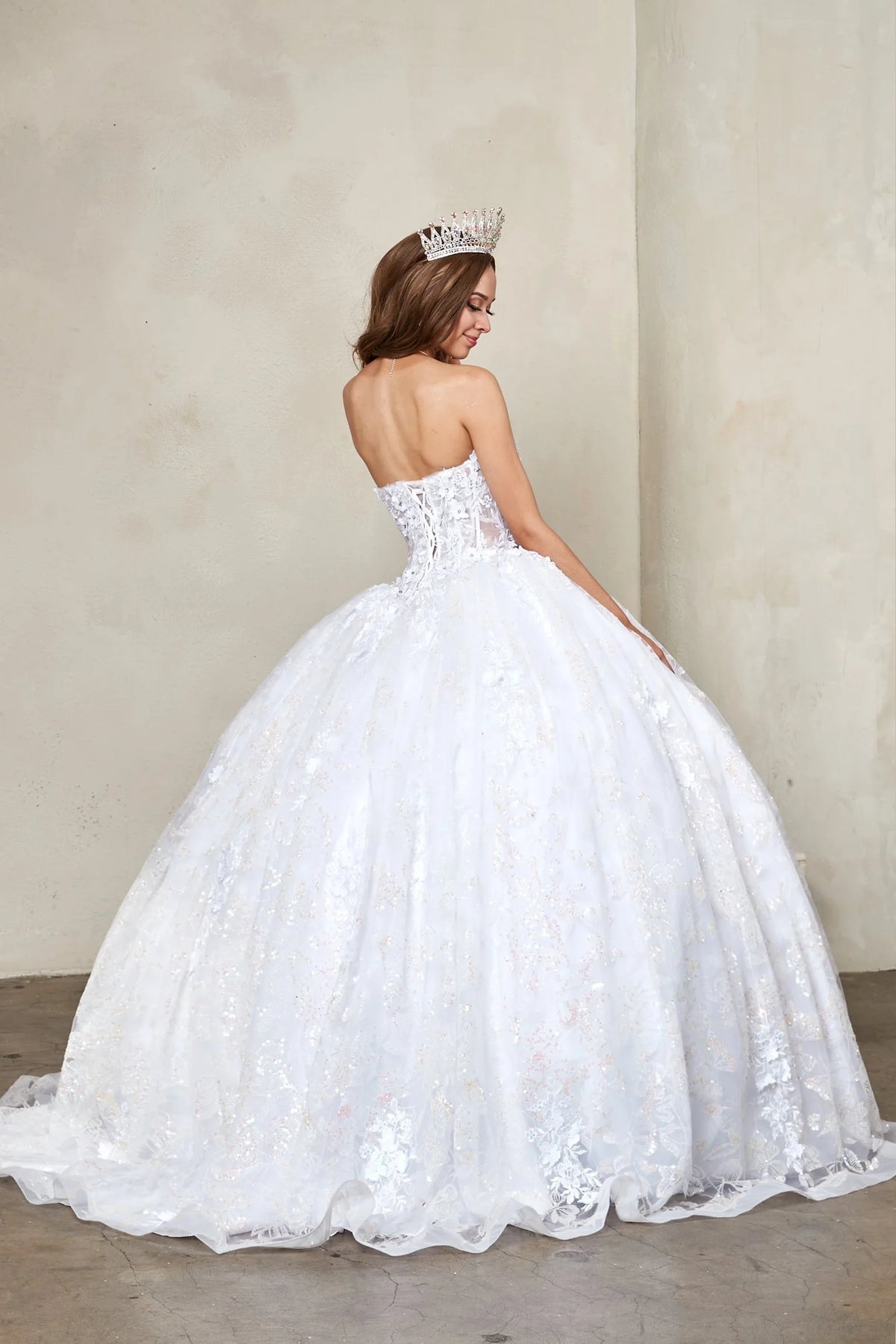 From behind, the White quinceañera ball gown reveals a fitted back and the dimensional finish of the skirt.