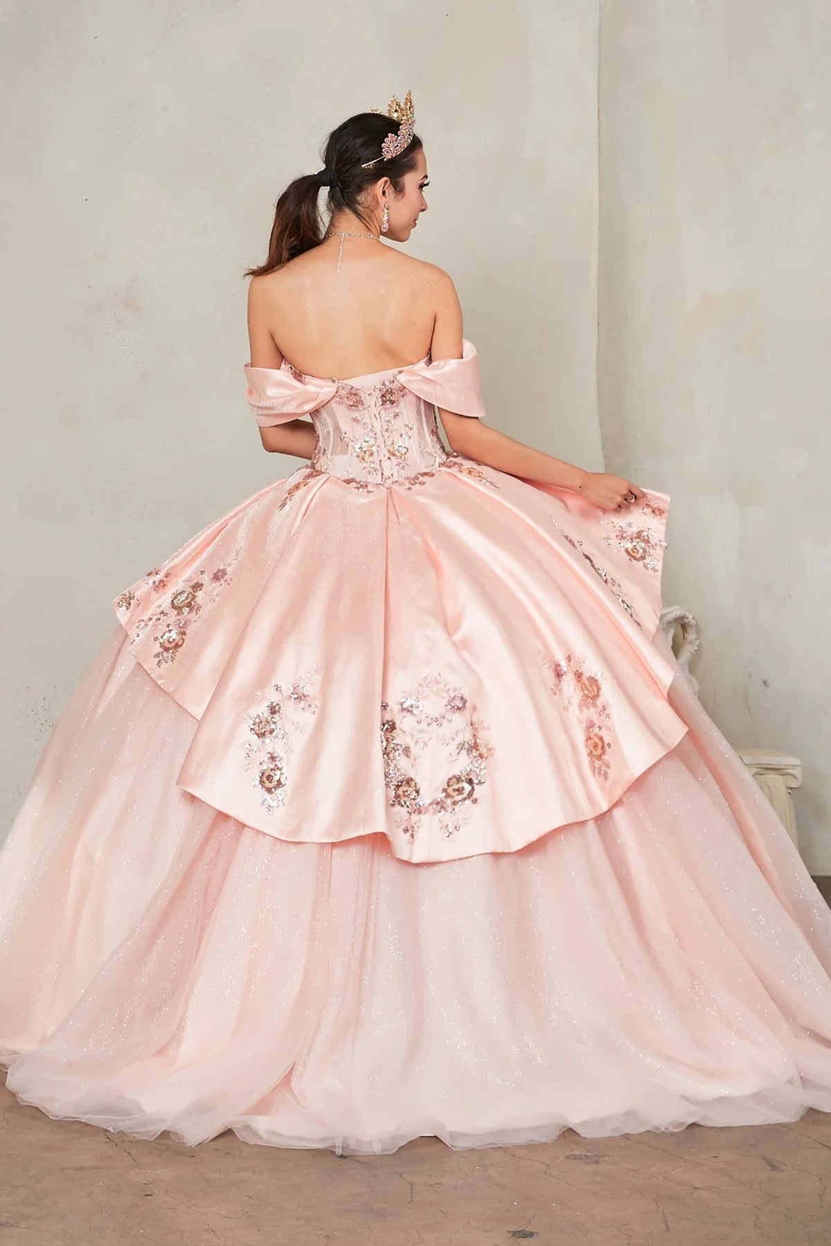 From behind, the Blush Pink quinceañera ball gown reveals a shaped lace-up back and the sweep of the full skirt.