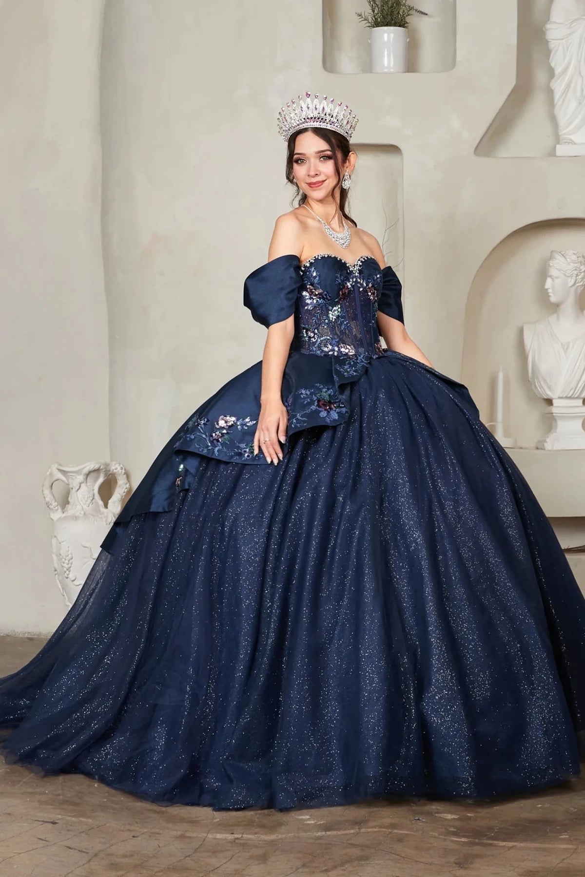Jeweled satin bodice with embroidered peplum defines the Navy quinceañera dress in this detailed view.