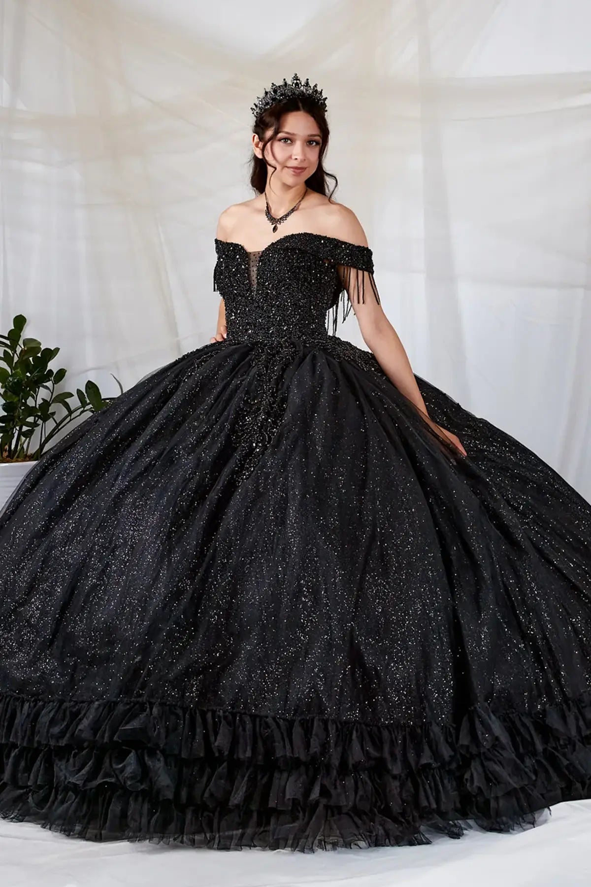 Side View of a woman wearing Classic black gown with beaded bodice off-shoulder styling and tiered skirt design