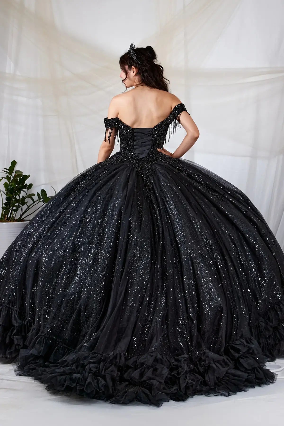 Back-Facing of a woman wearing Black formal gown featuring layered ruffle skirt structured back and flowing silhouette