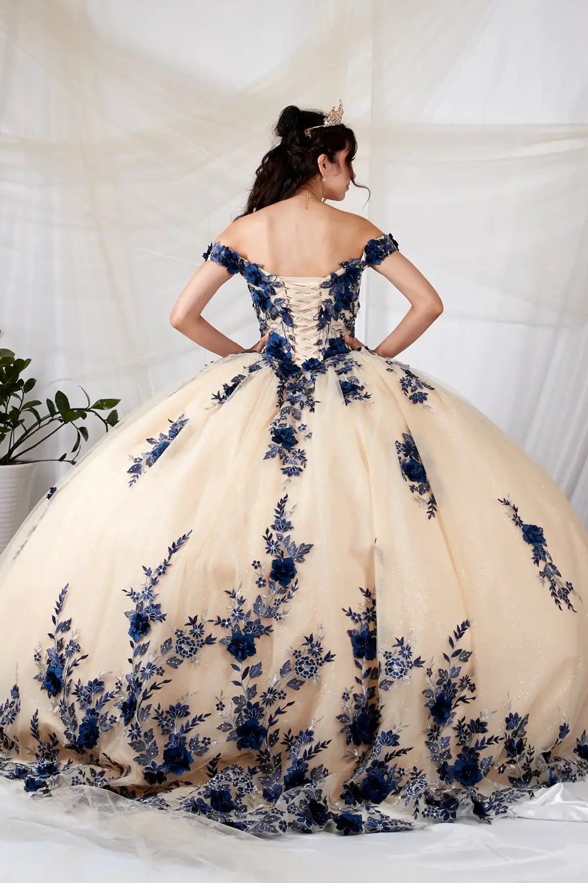Back-Facing of a woman wearing Champagne burgundy formal gown featuring full layered skirt extended hem and elegant silhouette