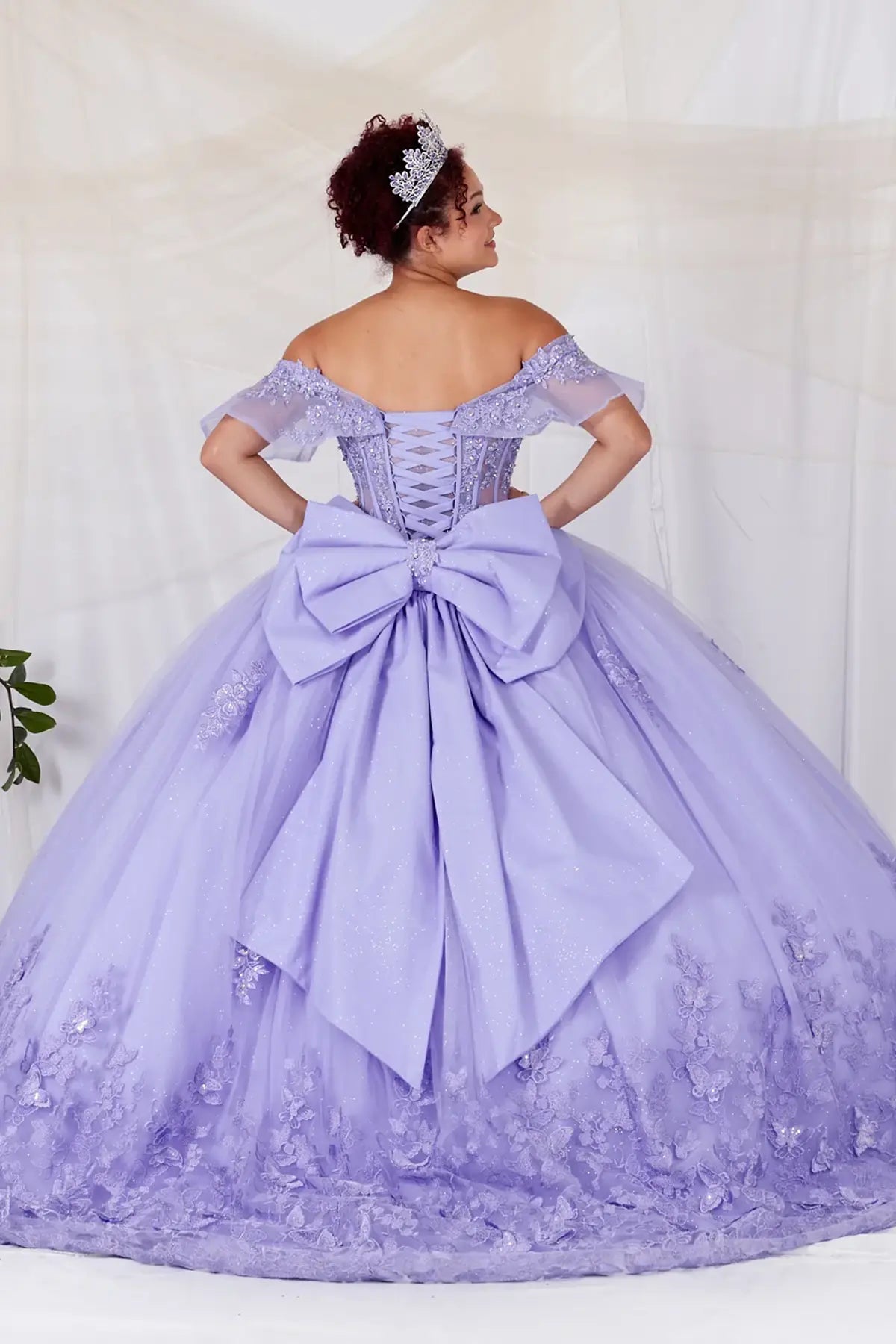 Back-Facing of a woman wearing Lilac formal gown featuring structured back flowing glitter tulle skirt and soft layered silhouette