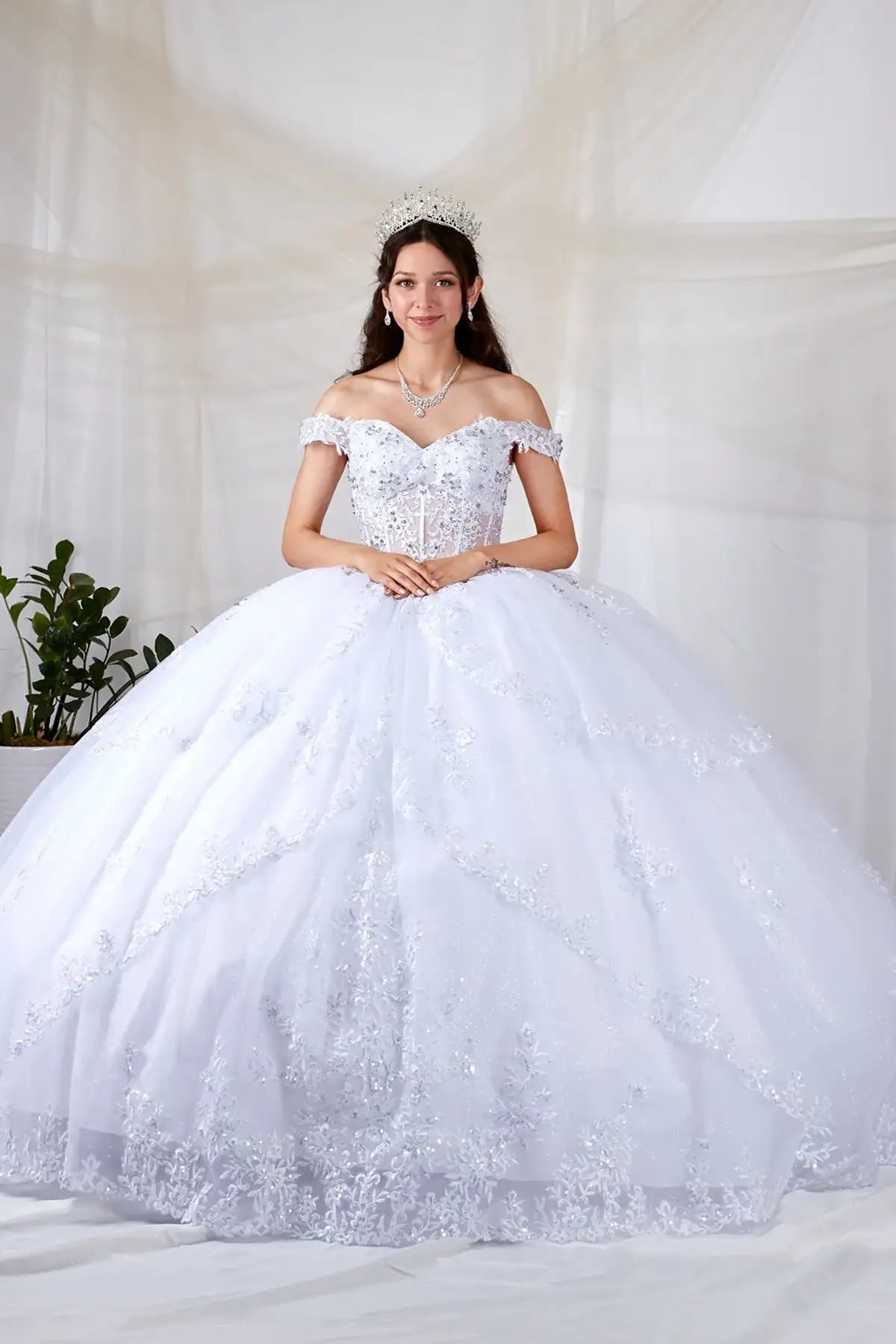 Front-Facing of a woman wearing White ball gown with sheer sweetheart neckline off-shoulder bodice floral embroidery and layered glitter tulle skirt