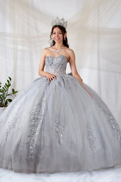 Front-Facing of a woman wearing Silver ball gown with sheer sweetheart neckline off-shoulder bodice floral appliques and embroidered glitter tulle skirt with bow accent