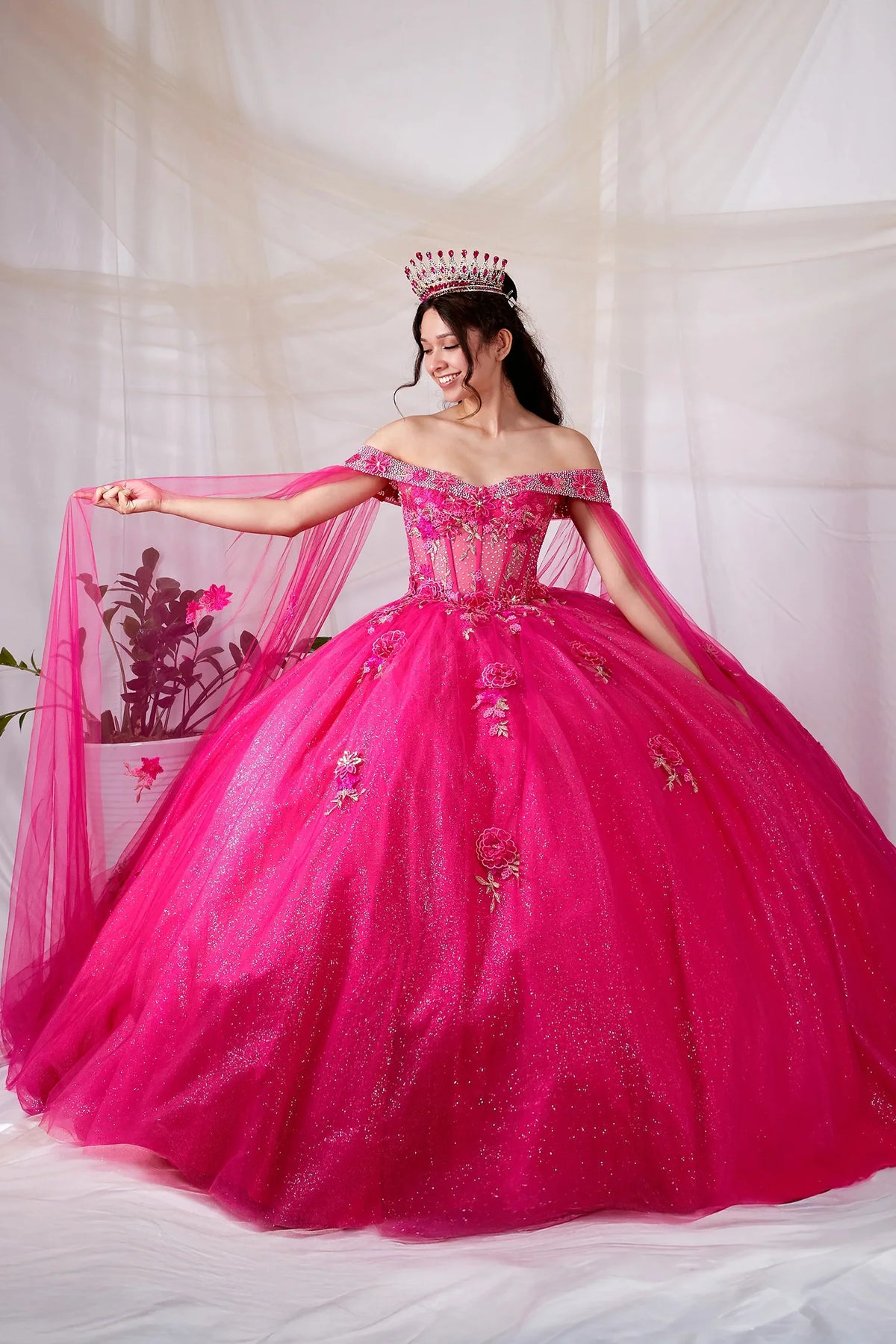 Hot pink quinceañera ball gown with sheer lace bodice, layered skirt and detachable cape