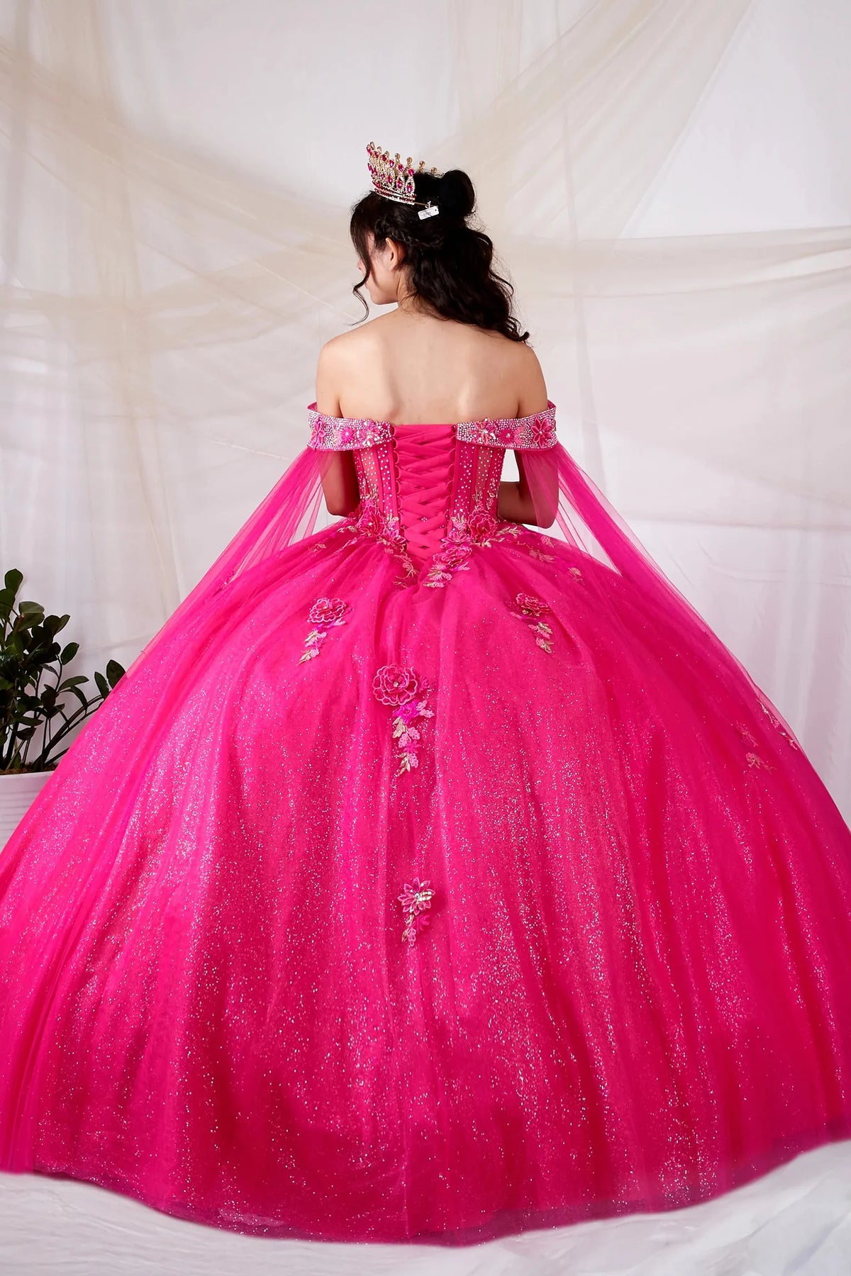 Hot pink quinceañera ball gown with sheer lace bodice and detachable cape
