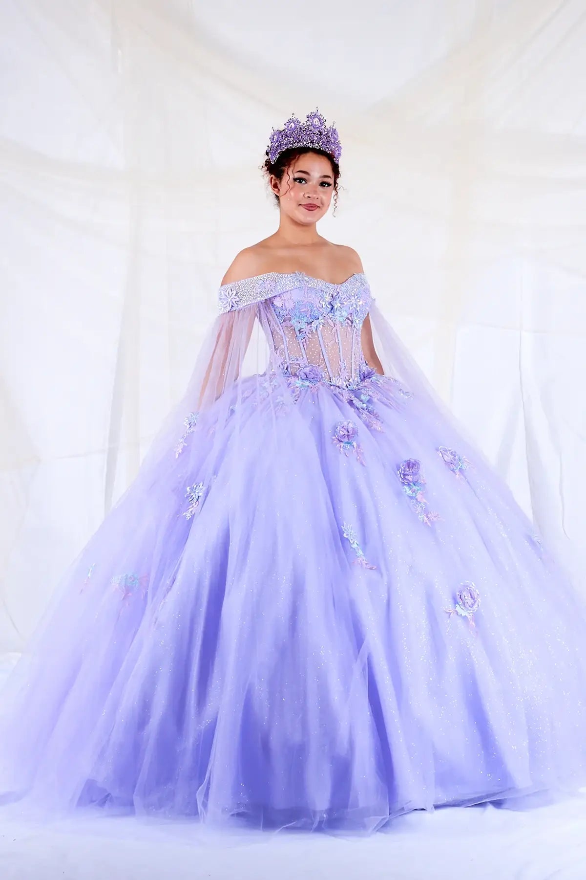 Lilac quinceañera ball gown with sheer lace bodice, off‑shoulder neckline and detachable cape
