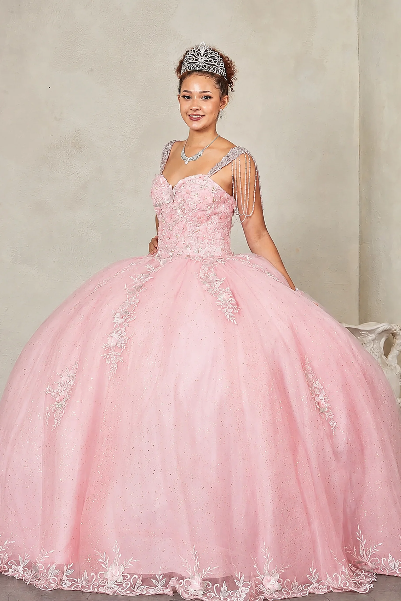 Blush quinceañera ball gown with sweetheart corset bodice framed by bead-fringed cap sleeves