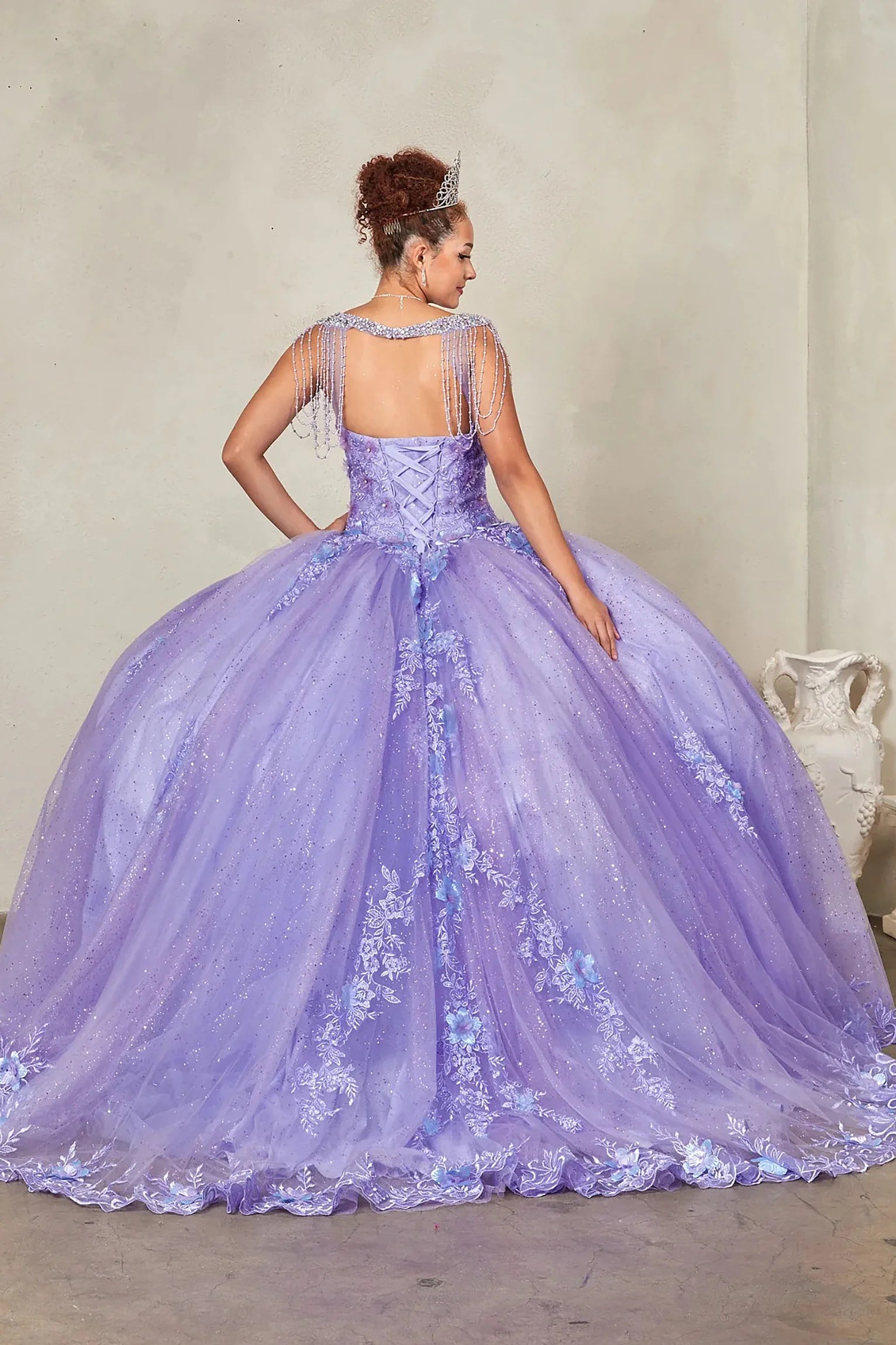 Lilac quinceañera ball gown extending into graceful train with lace appliqués accenting bead-fringed