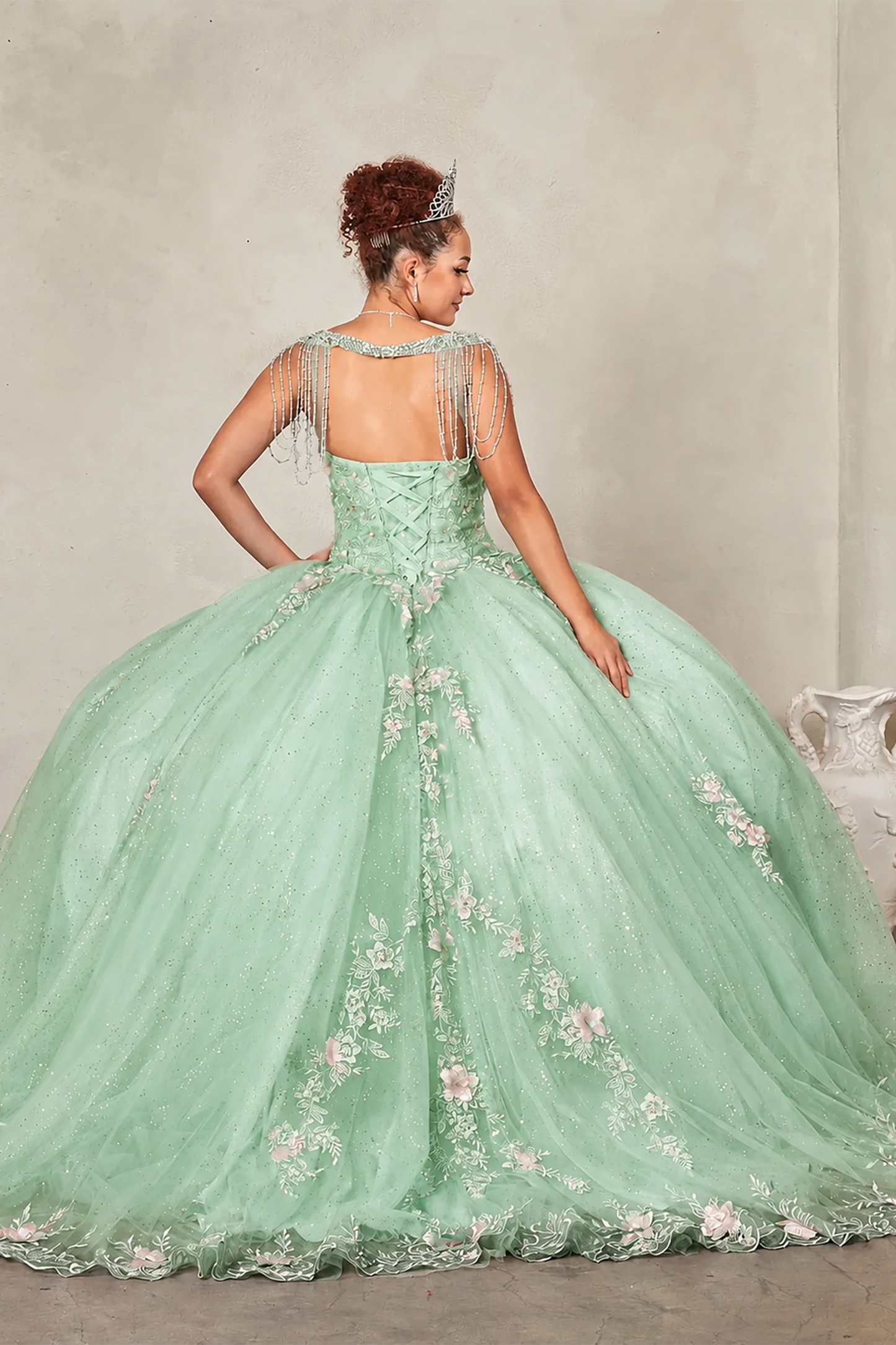 Sage quinceañera ball gown extending into graceful train with lace appliqués accenting bead-fringed