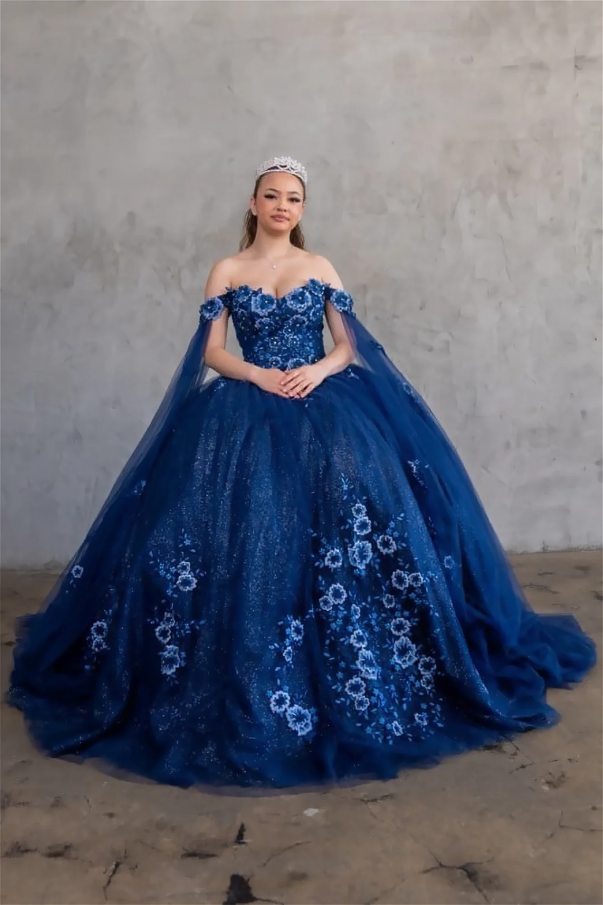 Navy quinceañera ball gown with 3D floral applique, detachable cape and glitter tulle skirt