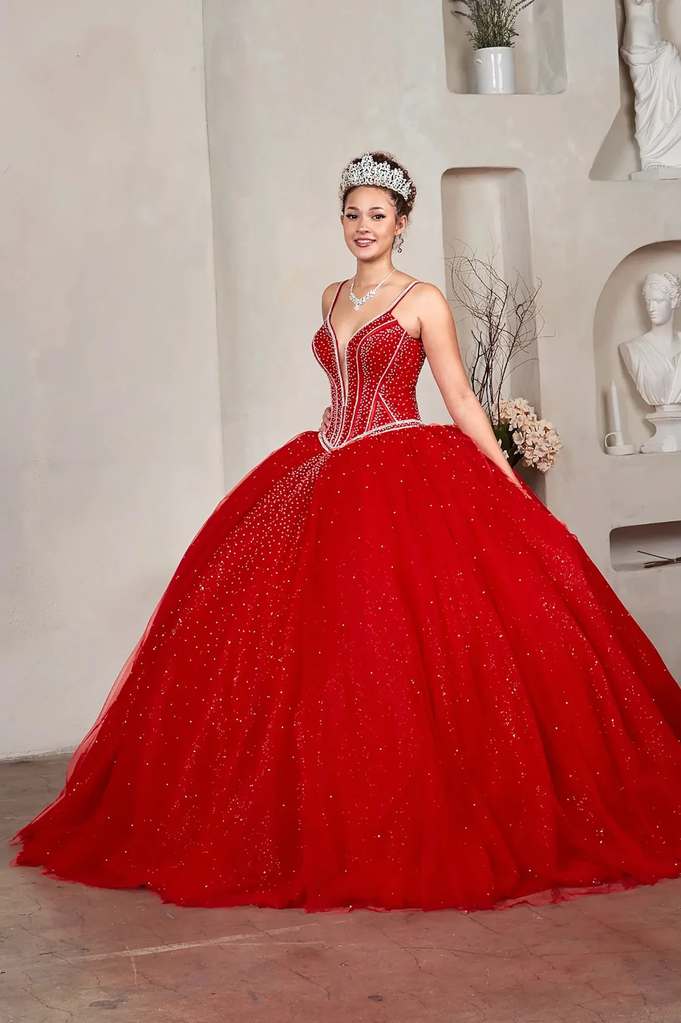 Red quinceañera ball gown with crystal beaded corset, V‑neckline, spaghetti straps and glitter tulle skirt