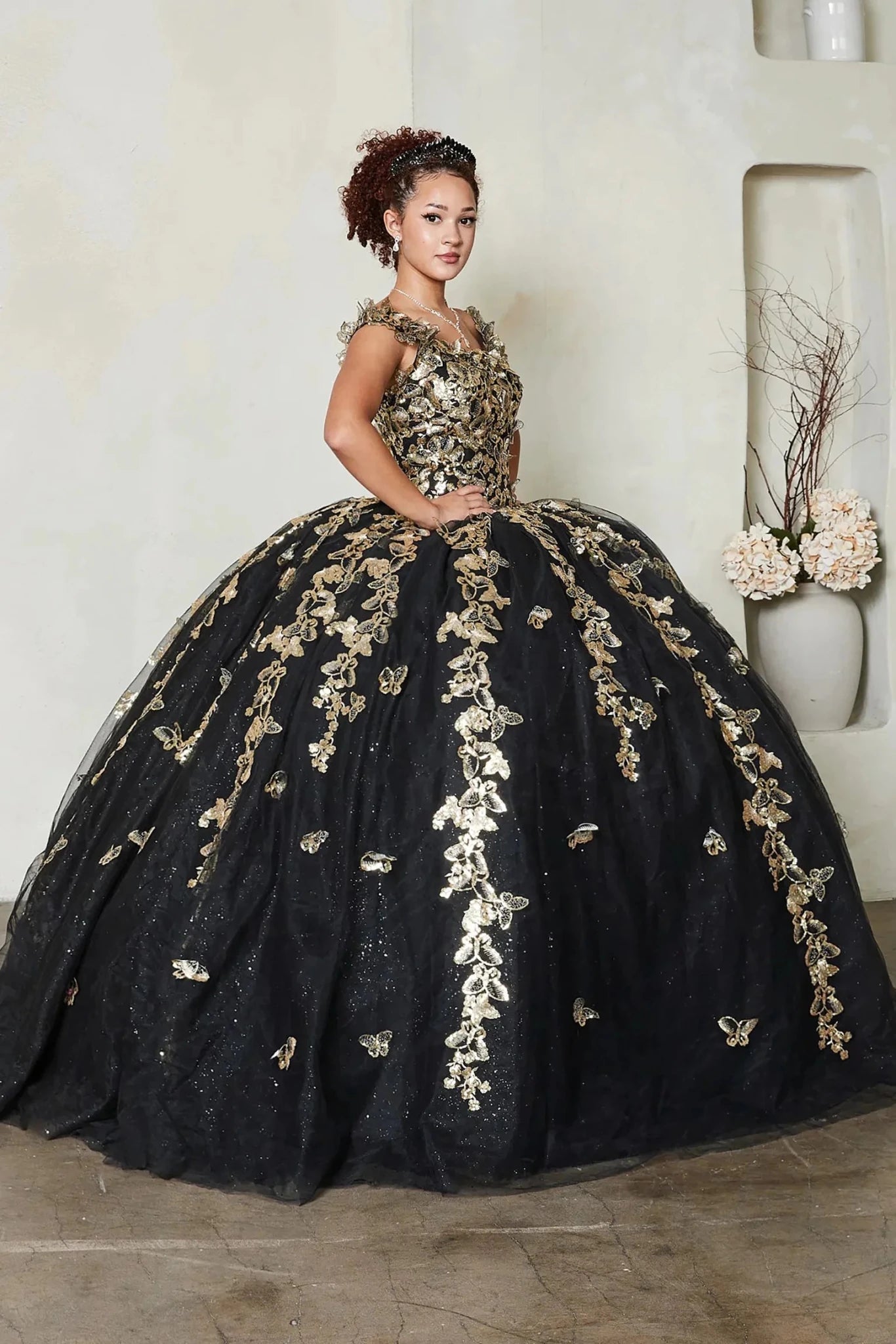 a voluminous black quinceanera ball gown with extensive gold floral embroidery and applique