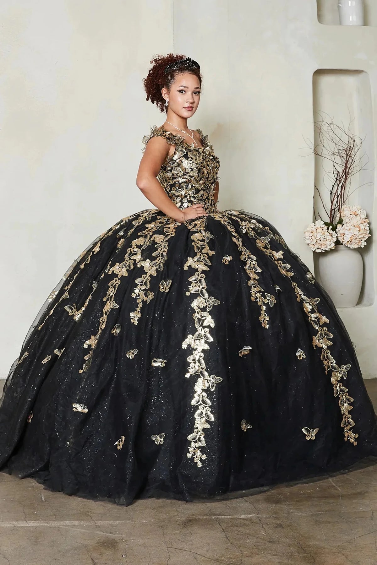a voluminous black quinceanera ball gown with extensive gold floral embroidery and applique
