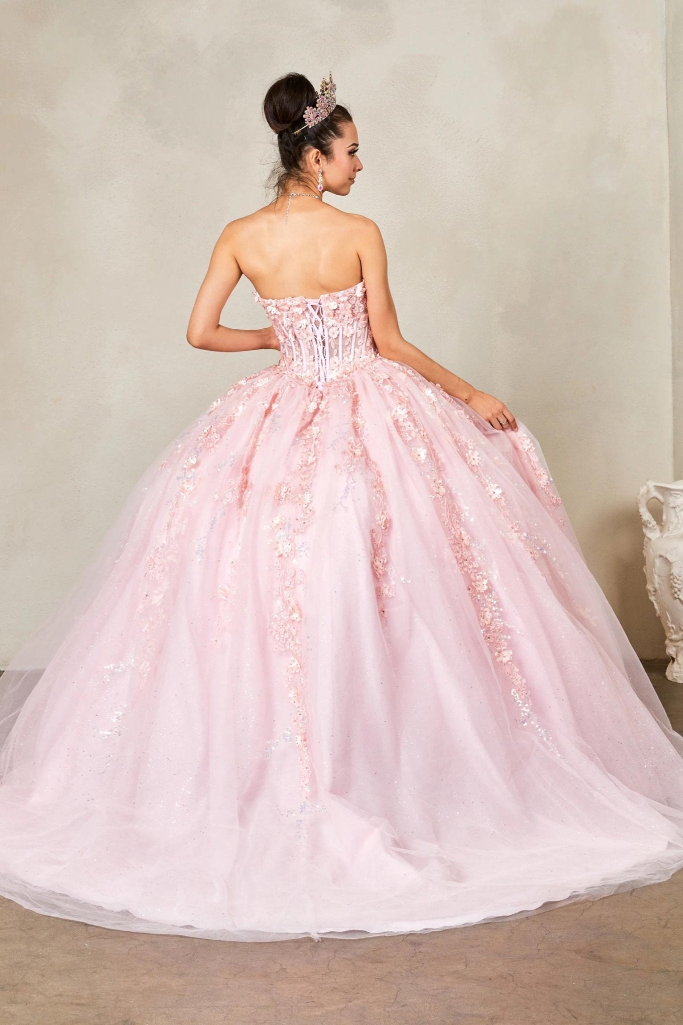a strapless light pink ball gown with a full tulle skirt and floral lace appliqué