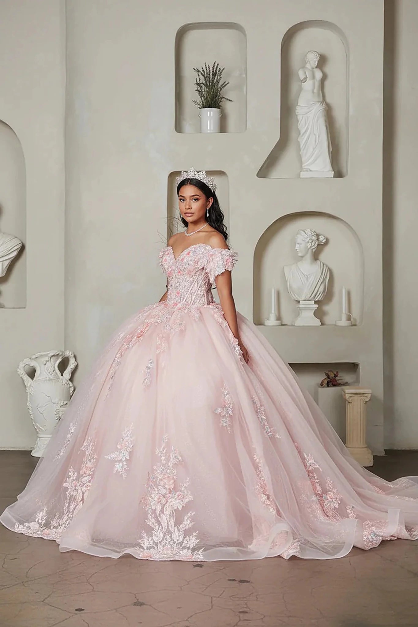 Blush quinceañera ball gown with off‑shoulder neckline, floral applique, crystal beaded bodice and glitter tulle skirt