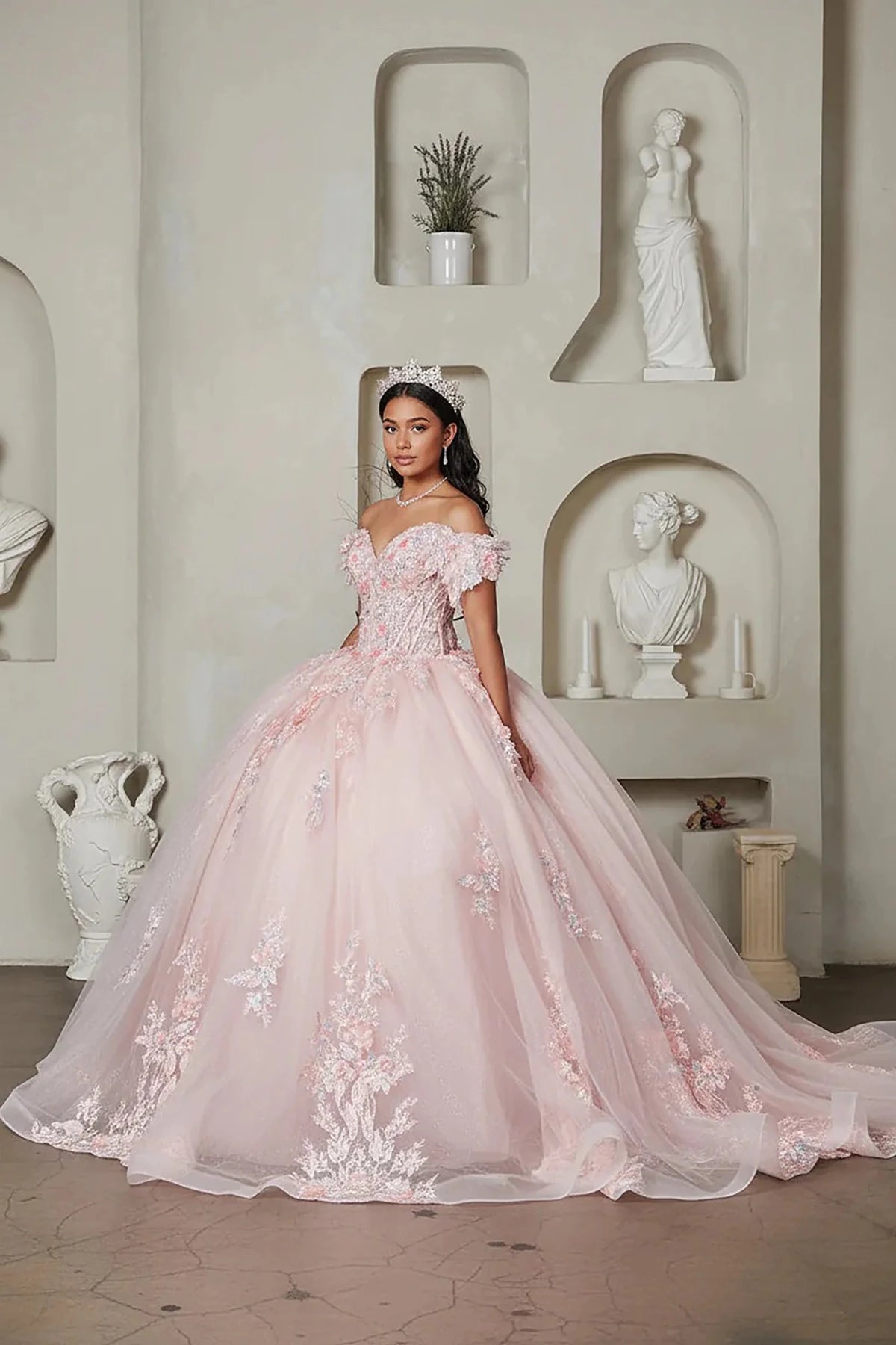 Blush quinceañera ball gown with off‑shoulder neckline, floral applique, crystal beaded bodice and glitter tulle skirt