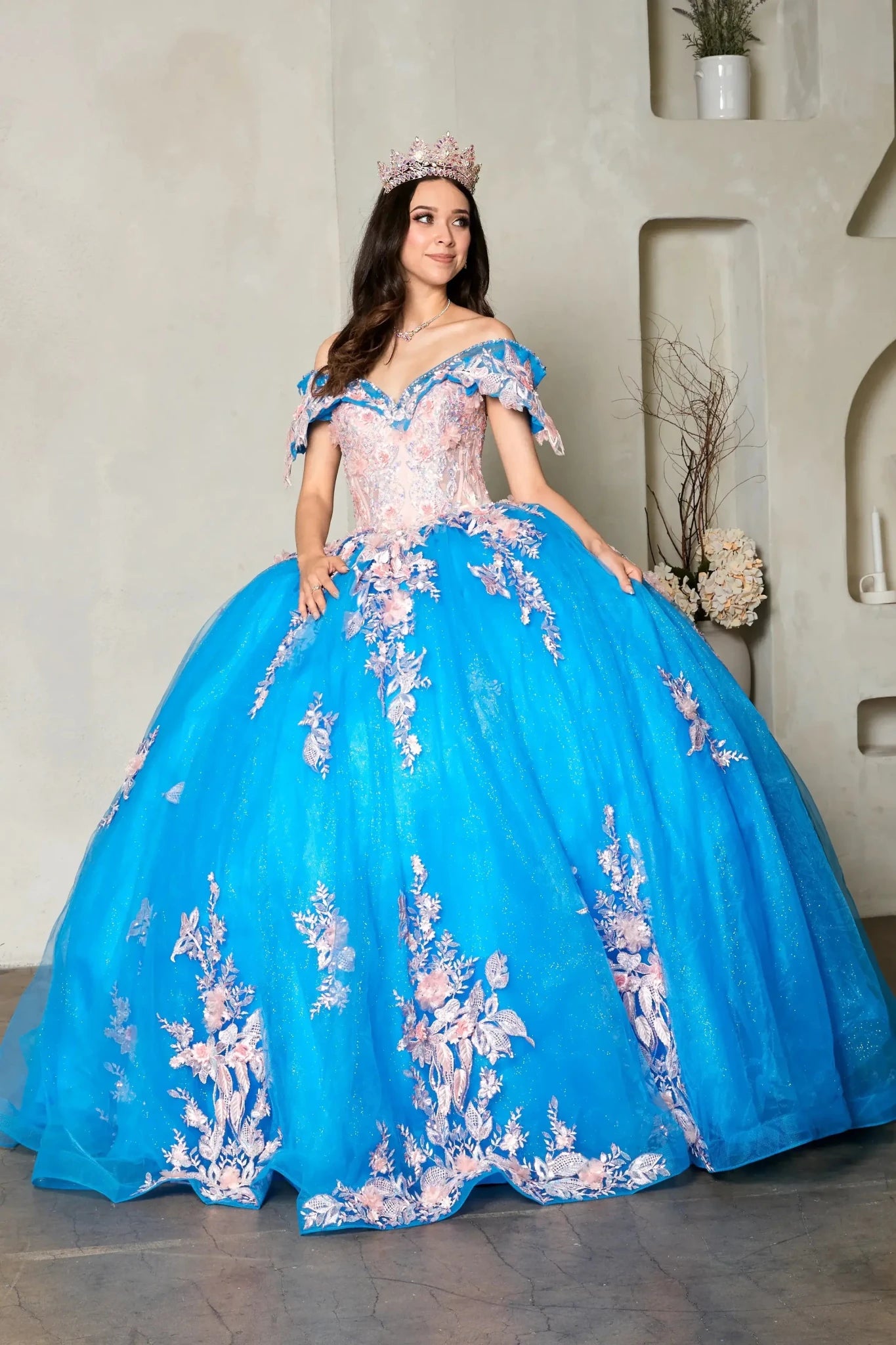 Turquoise quinceañera ball gown with off‑shoulder neckline, blush floral embroidery and glitter tulle skirt