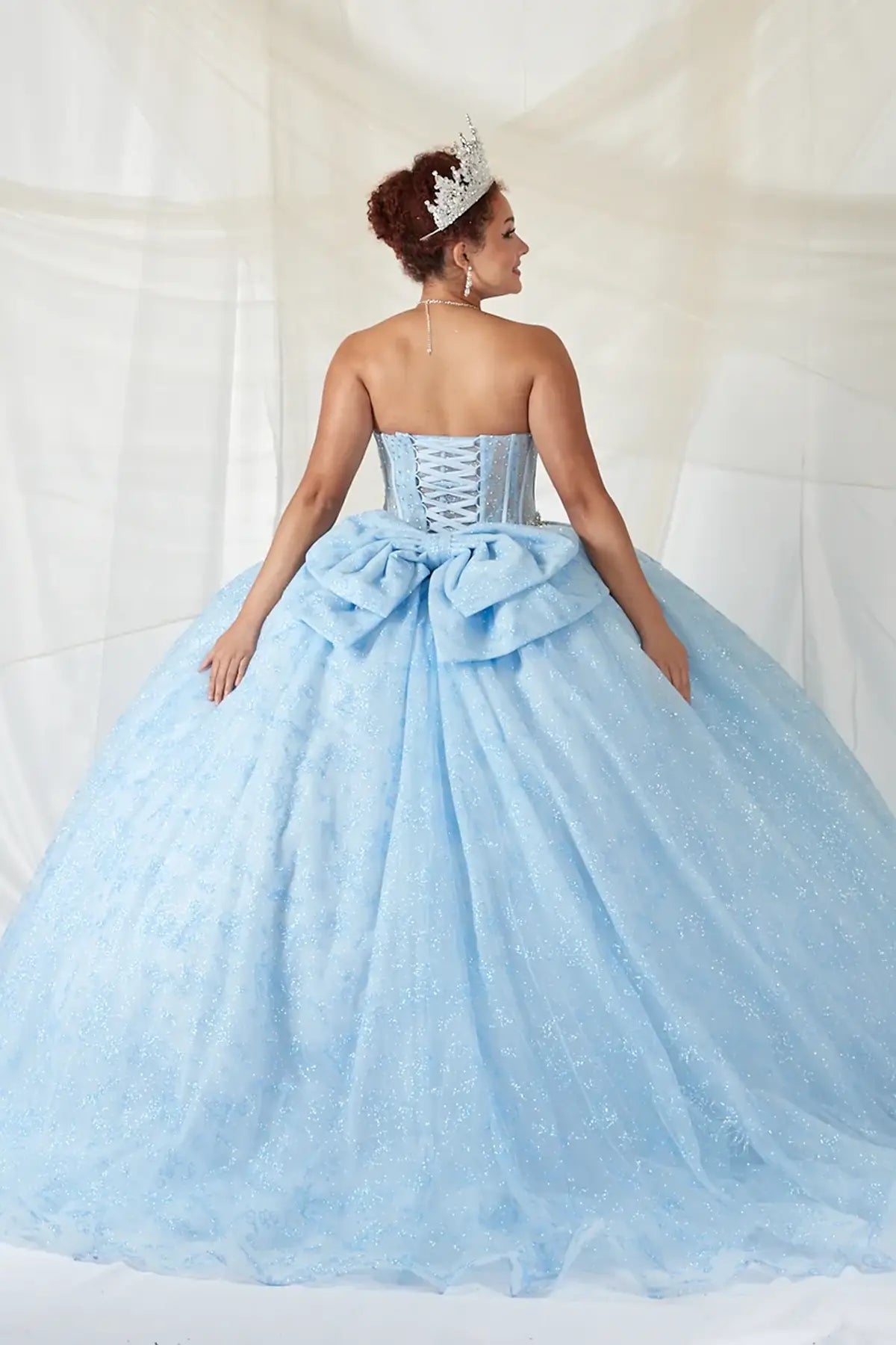 Bahama blue quinceañera ball gown with sheer corset bodice, crystal beading, glitter floral tulle and bow detail