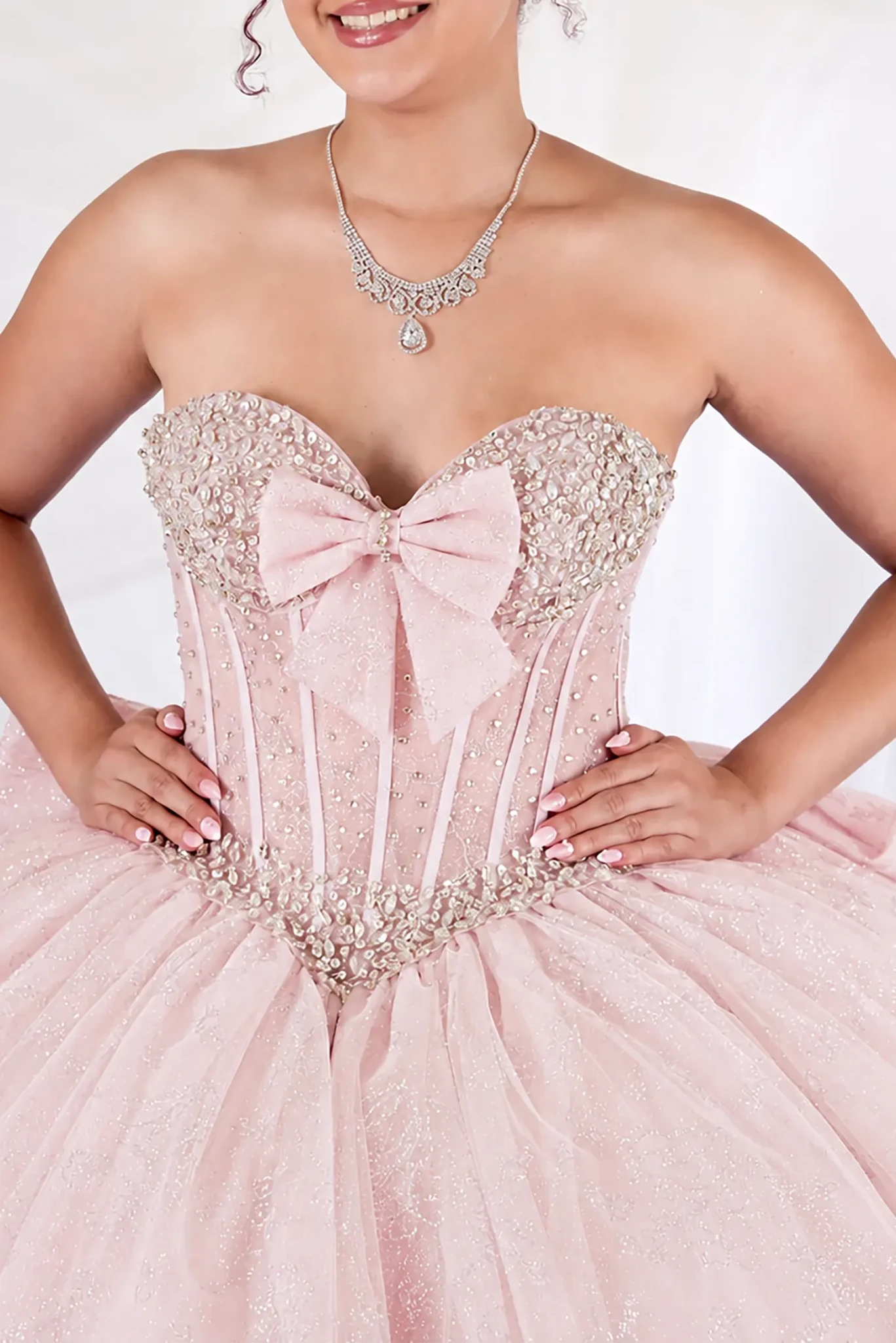 Pink quinceañera ball gown with beaded corset, sweetheart neckline, glitter floral tulle and bow detail