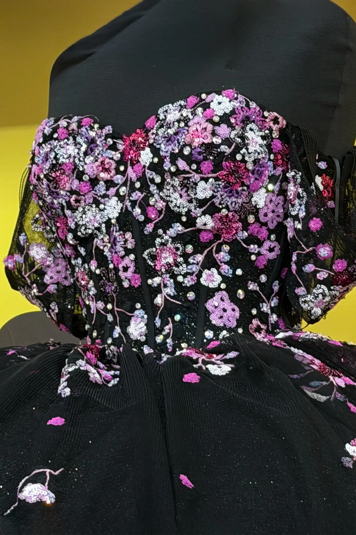 Black quinceañera ball gown with multicolor floral sheer bodice, basque waist and detachable bow