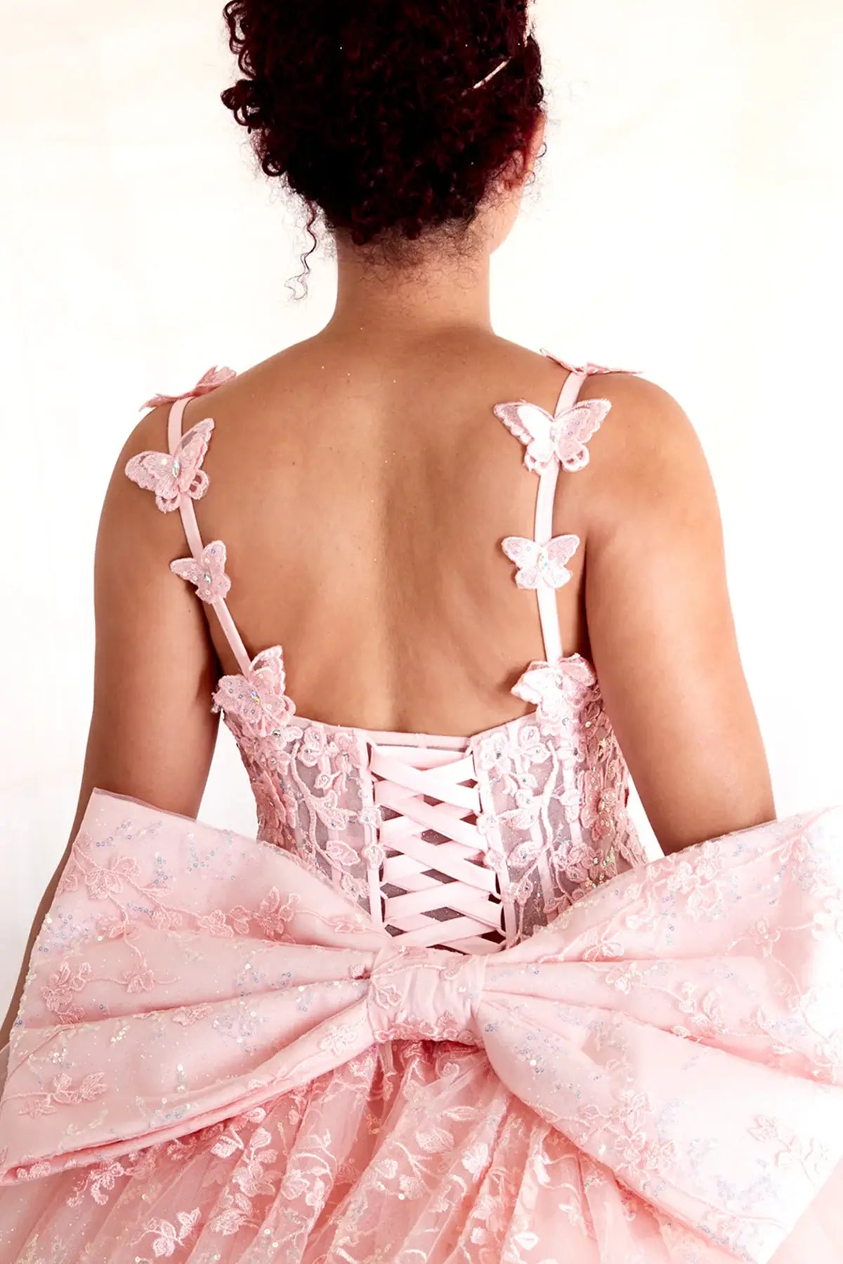 Blush quinceañera ball gown with 3D butterfly straps, layered tulle skirt and detachable bow