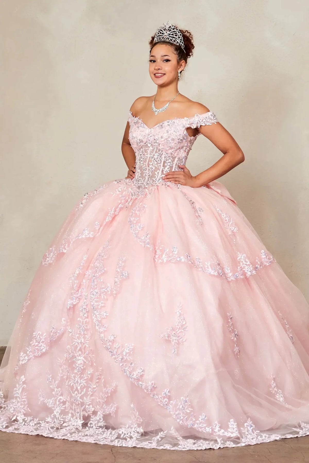 Blush quinceañera ball gown with sheer sweetheart bodice, floral embroidery and layered glitter tulle skirt