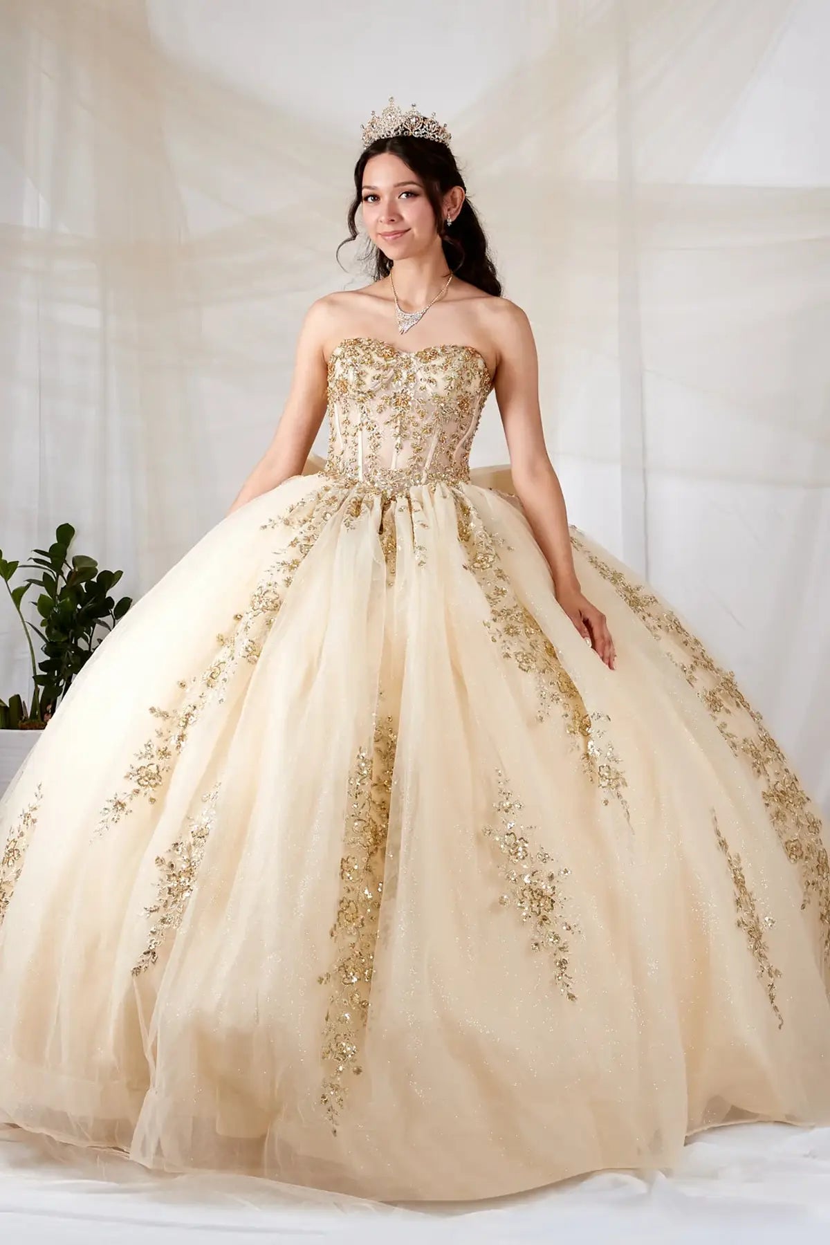 Champagne quinceañera ball gown with sheer sweetheart bodice, gold floral embroidery and glitter tulle skirt