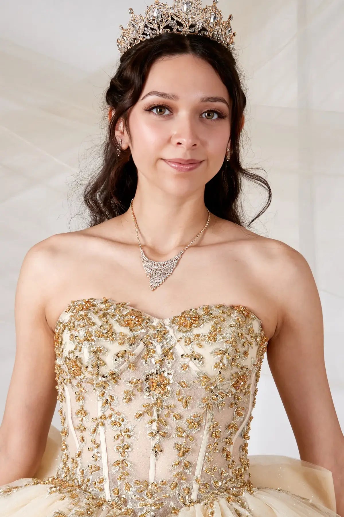 Champagne quinceañera ball gown with sheer sweetheart bodice, gold floral embroidery and glitter tulle skirt