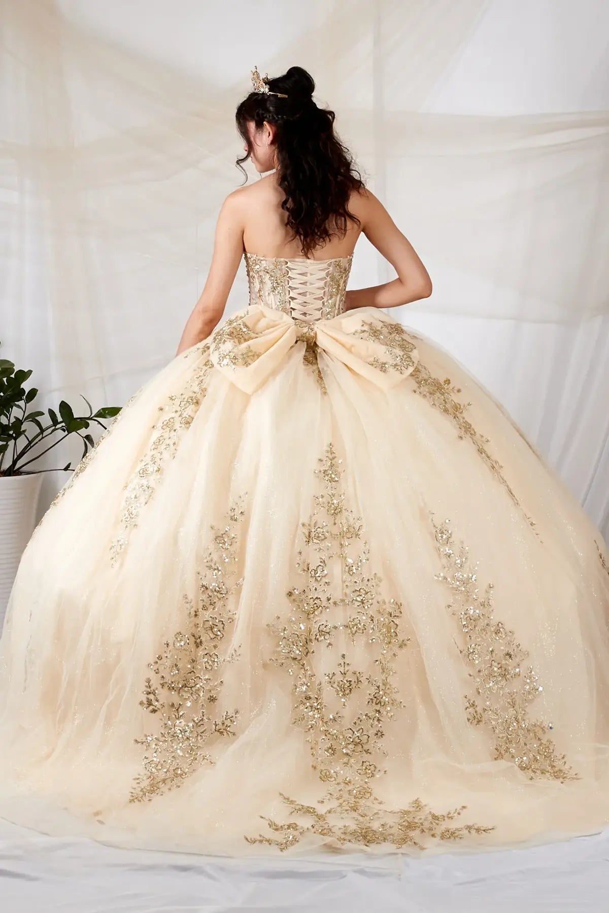 Champagne quinceañera ball gown with sheer sweetheart bodice, gold floral embroidery and glitter tulle skirt
