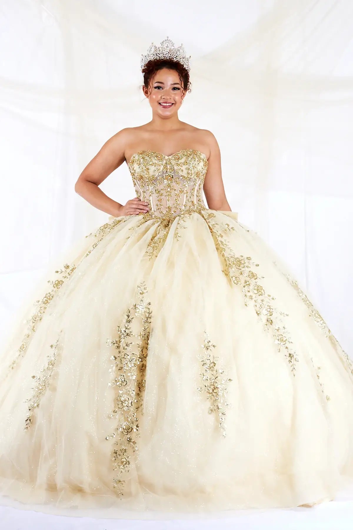 Champagne quinceañera ball gown with sheer sweetheart bodice, gold floral embroidery and glitter tulle skirt