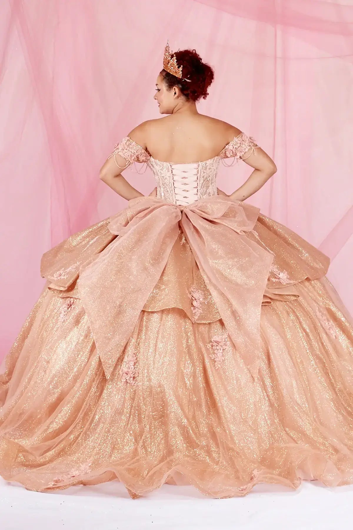 Rose gold quinceañera ball gown with beaded fringe straps, gold embroidered lace and ruffled train