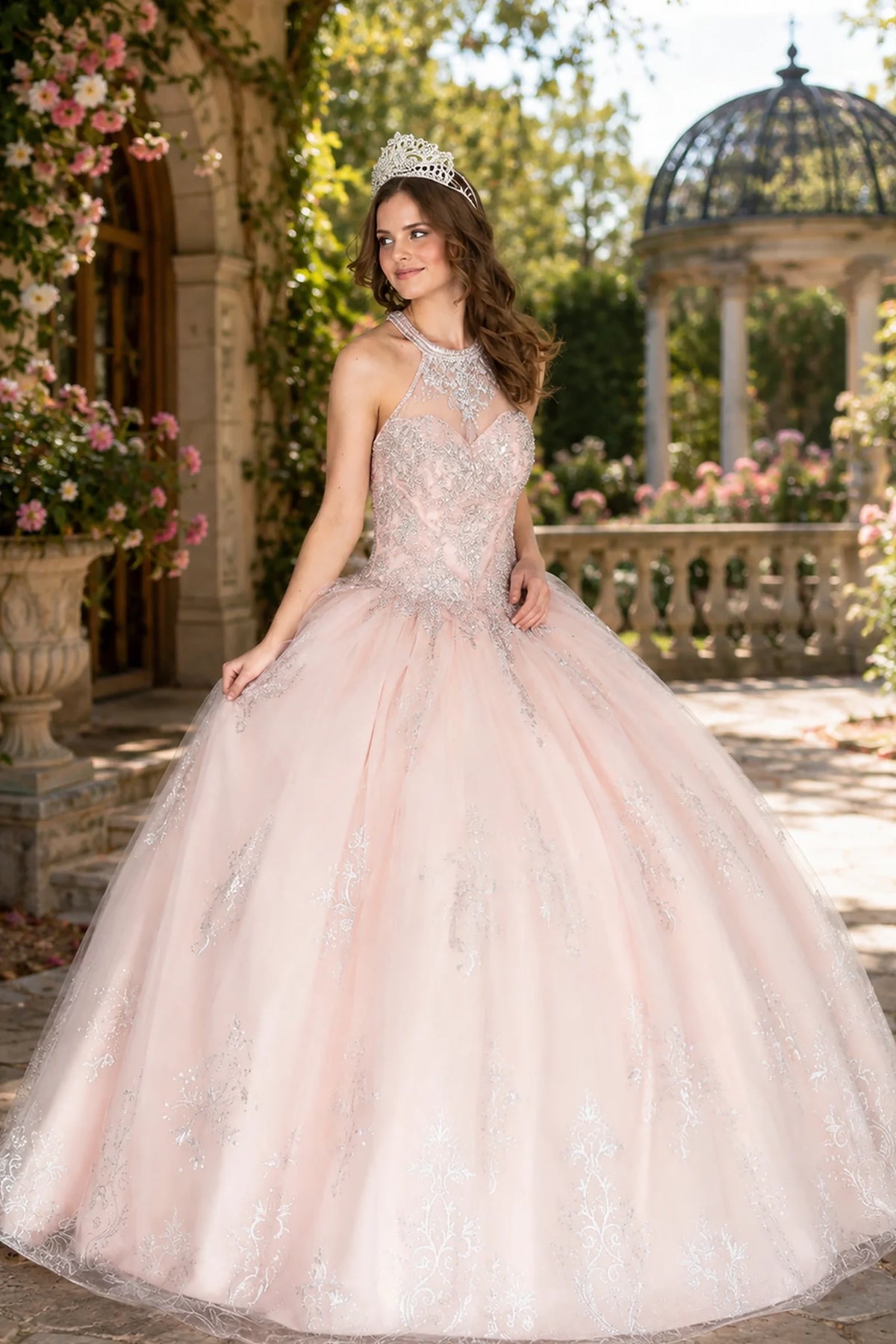 Blush Pink quinceañera dress showcases embroidered illusion bodice above softly glittered full ball skirt.