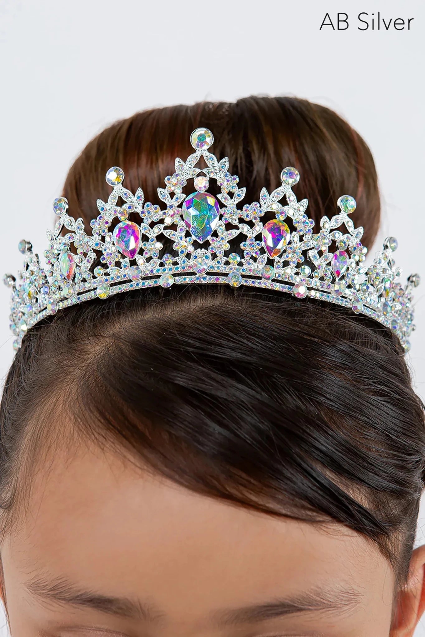 A silver jeweled tiara with iridescent rhinestones worn on a girl's hair