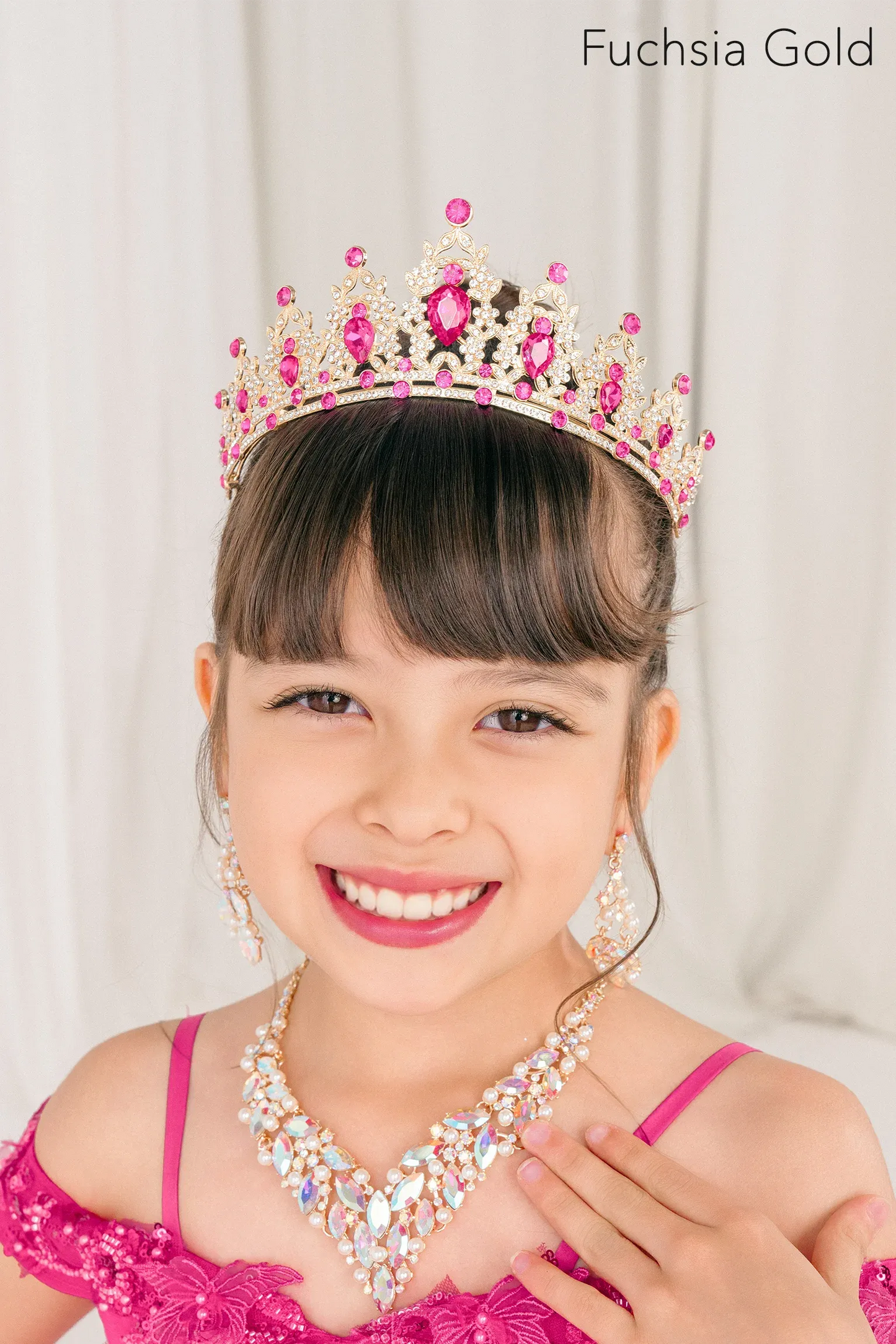 Young girl wearing a fuchsia gold tiara and necklace