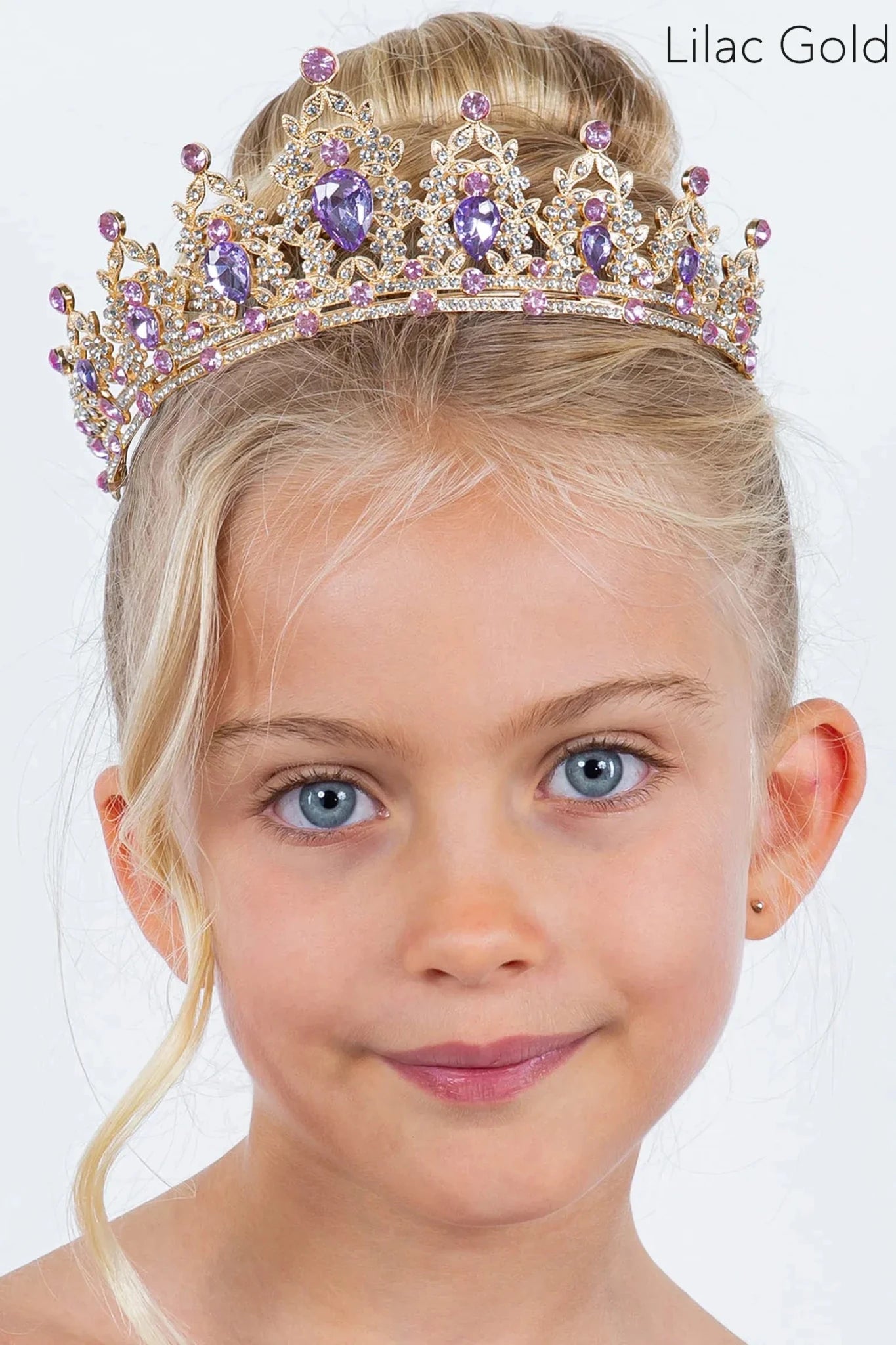 A young girl wears a gold tiara adorned with purple and pink rhinestones