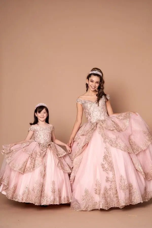 Front-Facing of a woman wearing Blush and gold quinceanera gown with off-shoulder sleeves intricate embroidery and voluminous layered skirt